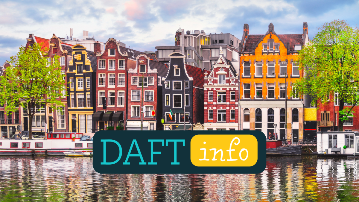 Colorful historic buildings along a canal with boats and green trees in Amsterdam