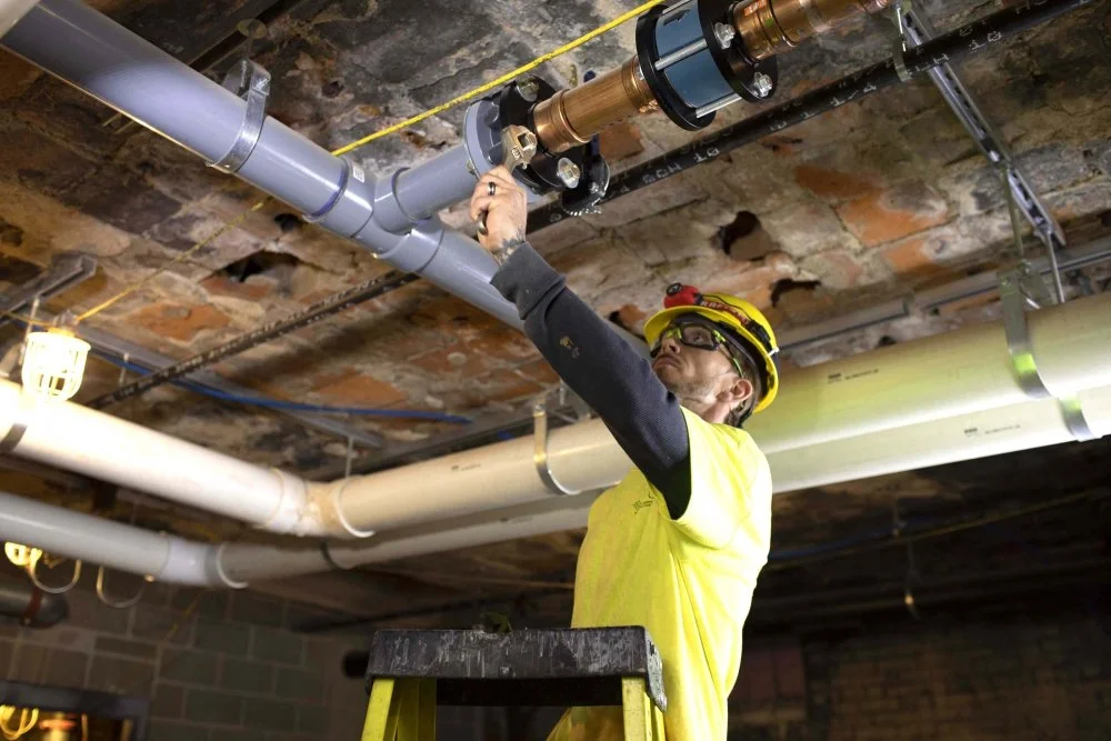 Plumber working on overhead commercial piping