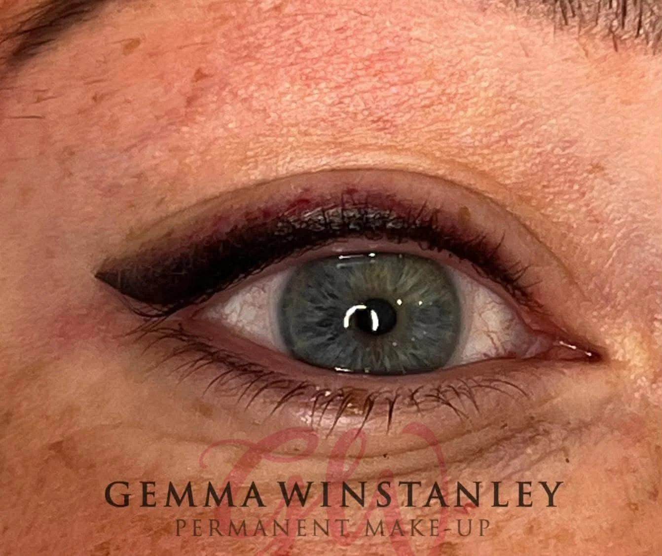 Close-up of a woman's eye with dark, winged eyeliner and subtle eyeshadow, surrounded by skin with visible pores and light makeup, featuring the logo and text for "Gemma Winstanley Permanent Make-up" at the bottom.
