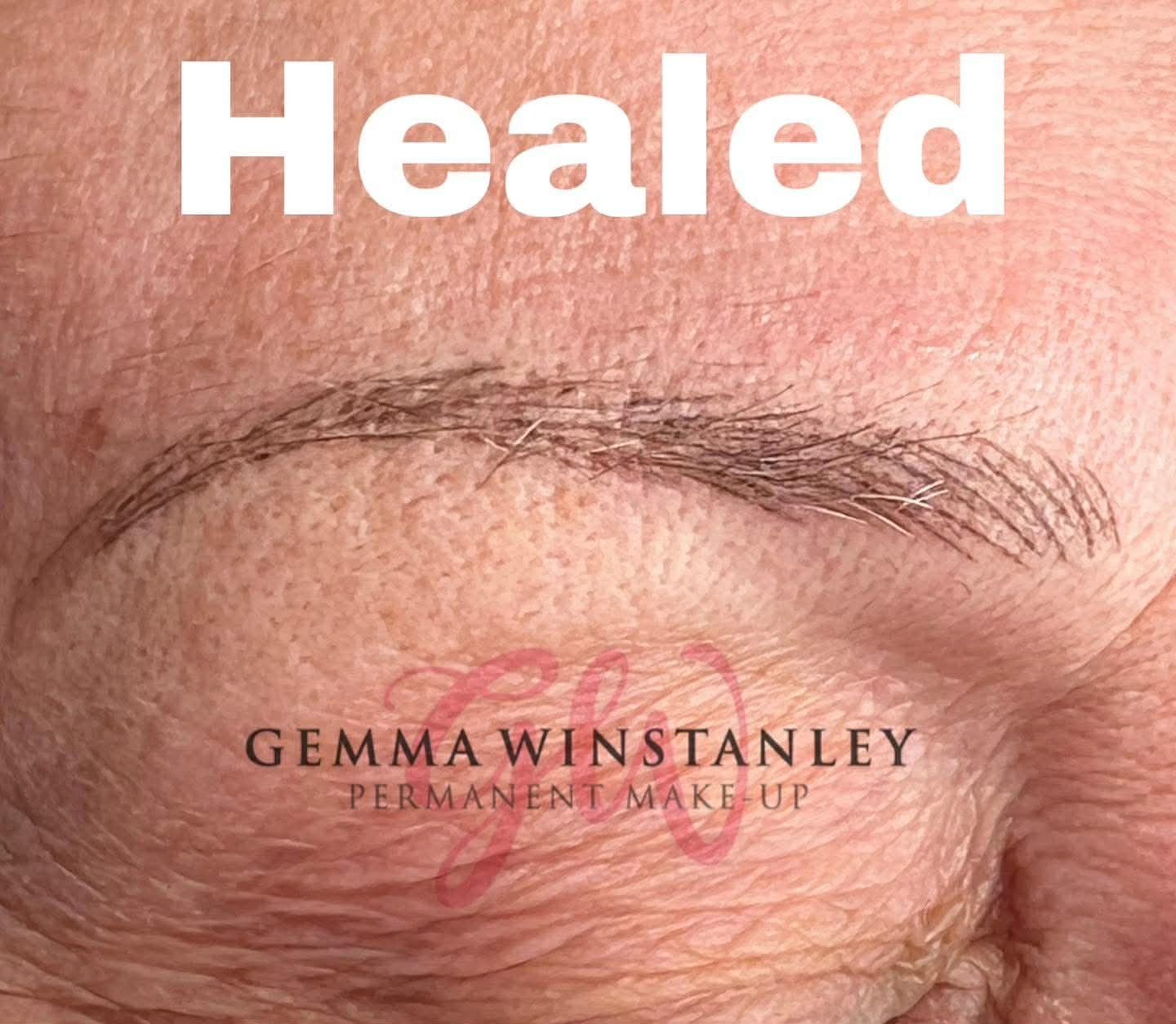 Close-up of a person's eyebrow with the word 'Healed' at the top and the text 'Gemma Winstanley Permanent Make-up' beneath the eyebrow. The skin appears textured and natural.