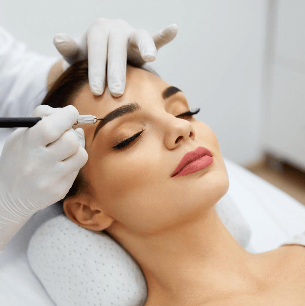 Woman receiving a cosmetic eyebrow procedure from a professional in a clinical setting.
