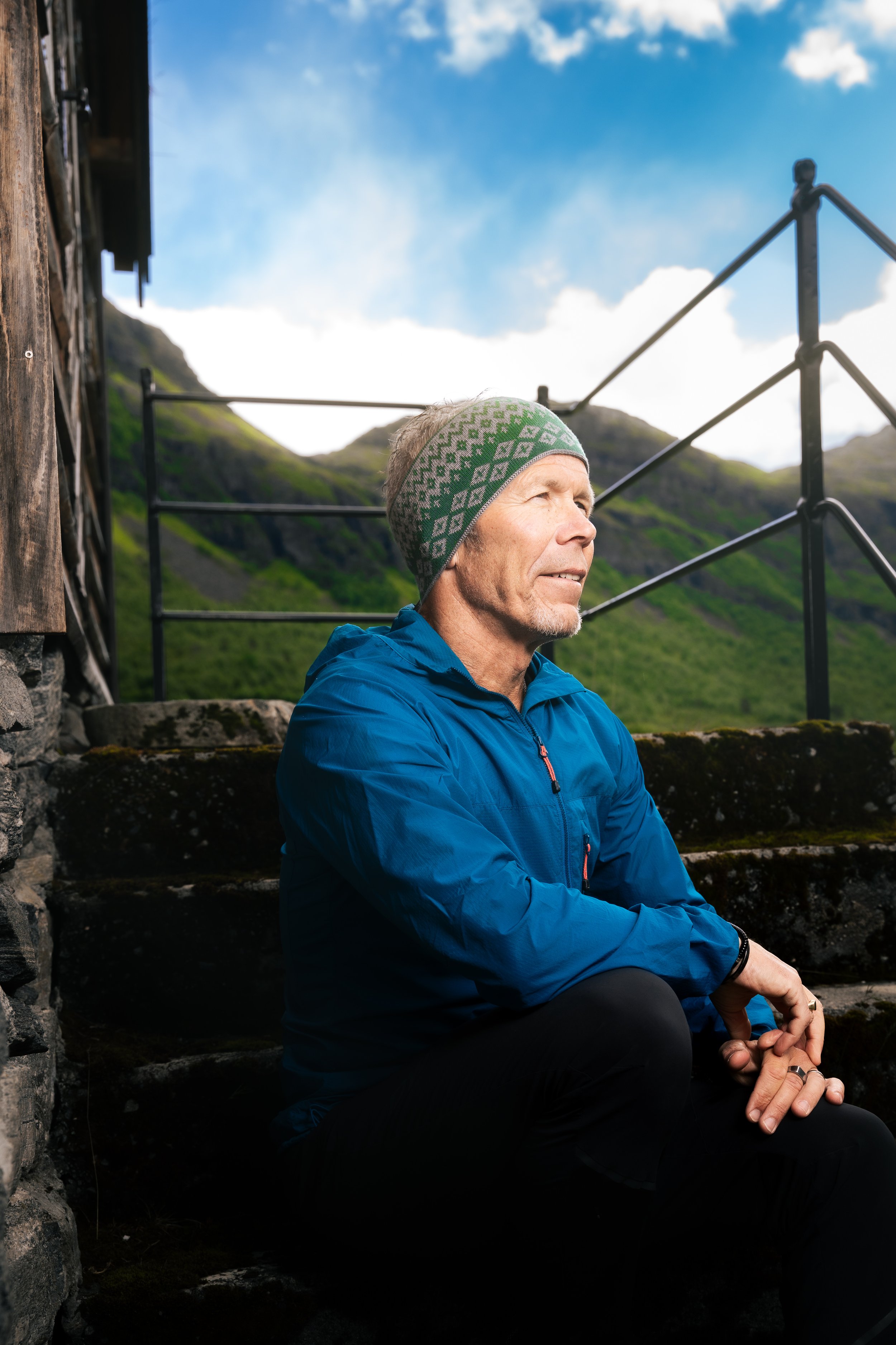 Miljøportrett av mann i blå jakke med fjellandskap i bakgrunnen – naturleg portrettfotografering utført av Karlsen Media.