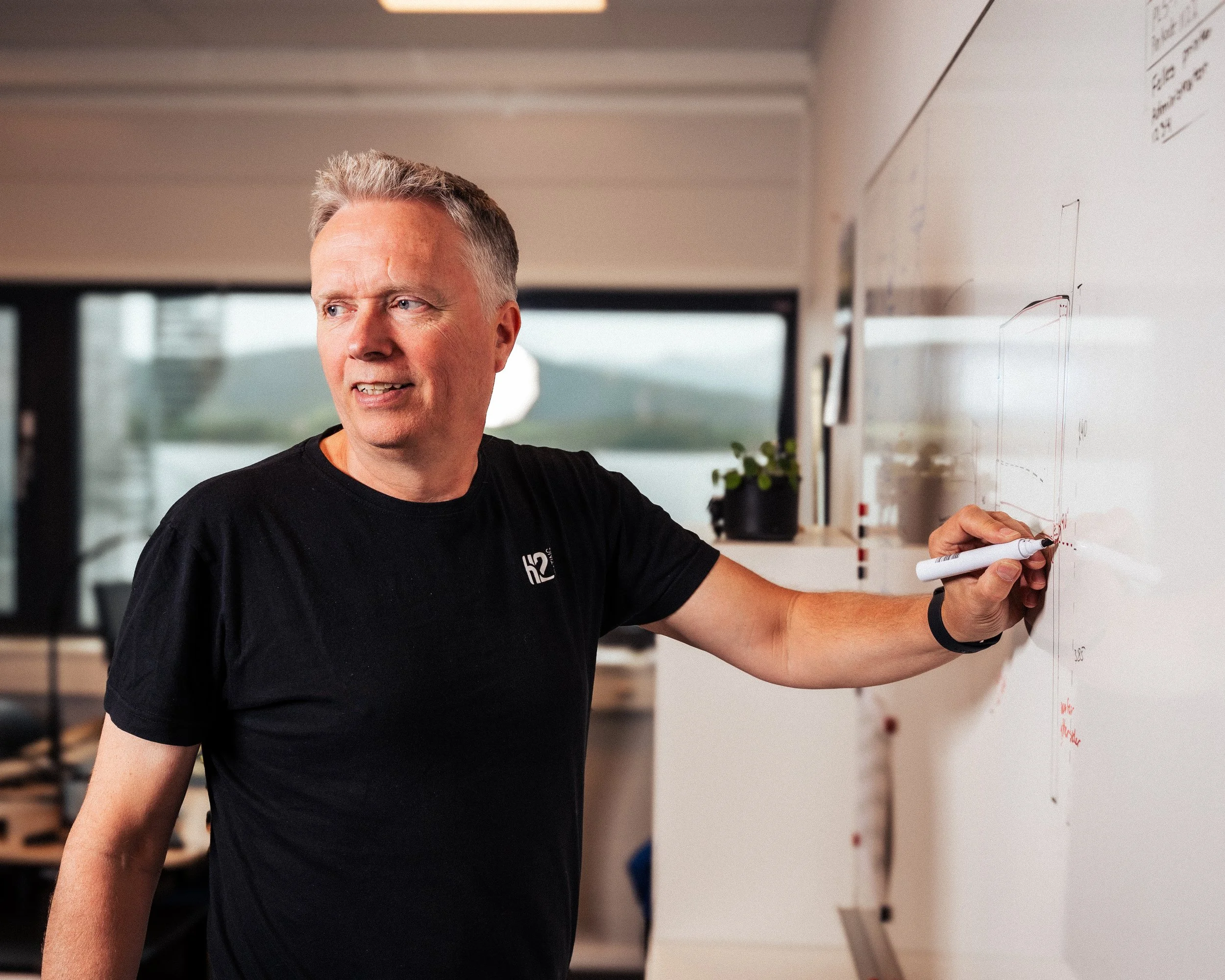 Profesjonelt bedriftsfoto av mann som presenterer ved ei tavle – miljøfotografering for bedrifter og organisasjonar.