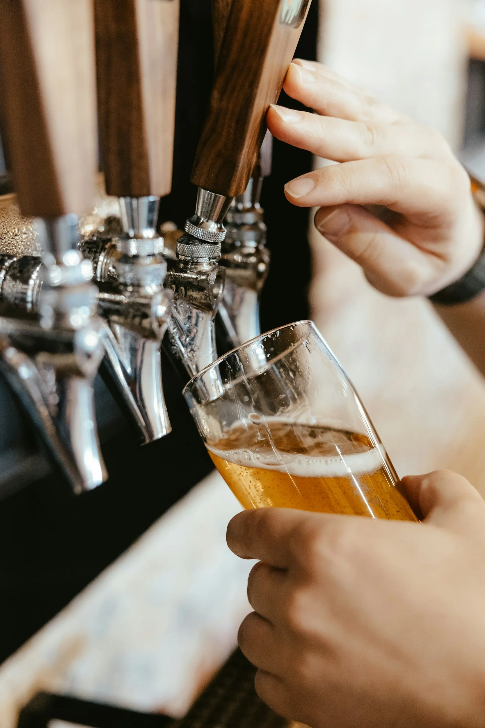A person pouring beer from tap into a glass.