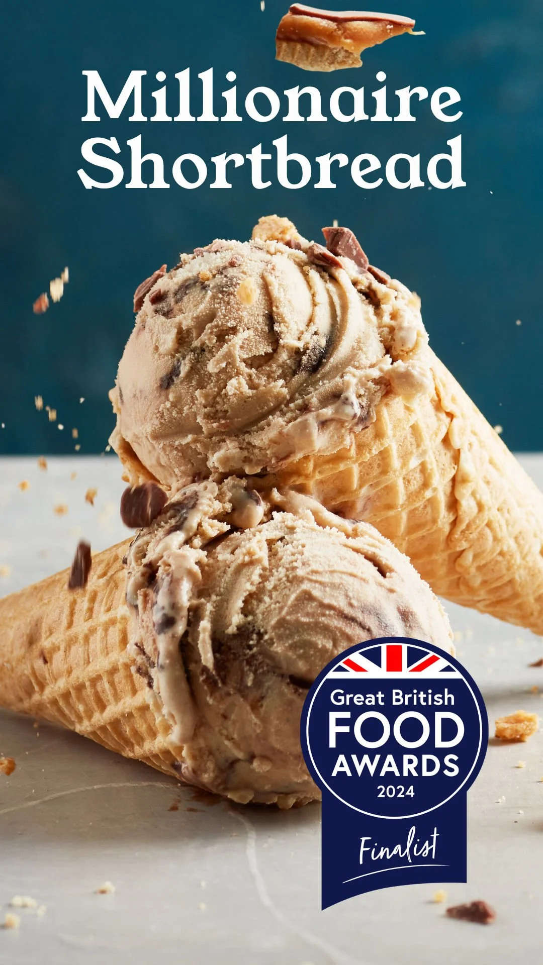 Two ice cream cones with chocolate and vanilla ice cream, one cone is topped with a cookie piece, on a gray surface with scattered crumbs, against a dark blue background, with text "Millionaire Shortbread" and a badge for the Great British Food Awards 2024 finalist.