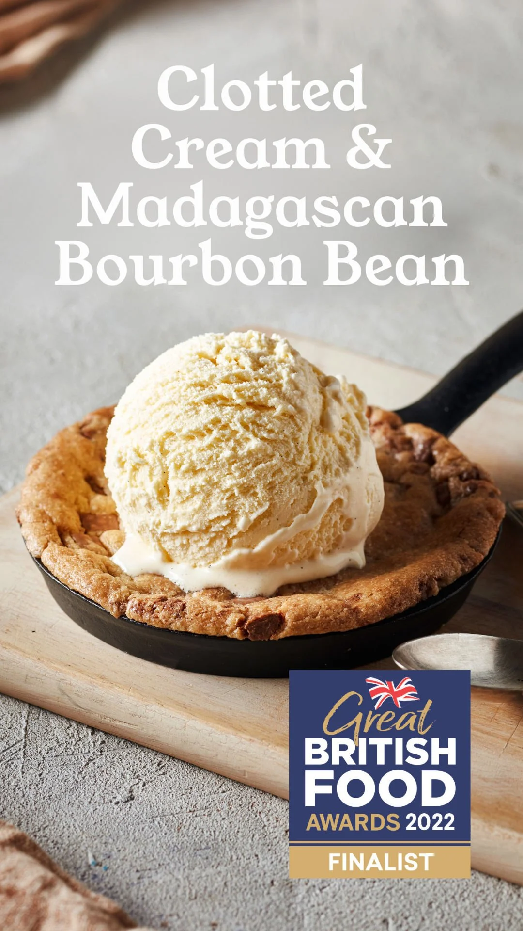 A skillet with a baked tart topped with a scoop of vanilla ice cream, labeled as 'Clotted Cream & Madagascan Bourbon Bean,' with a badge indicating it was a finalist in the 2022 Great British Food Awards.