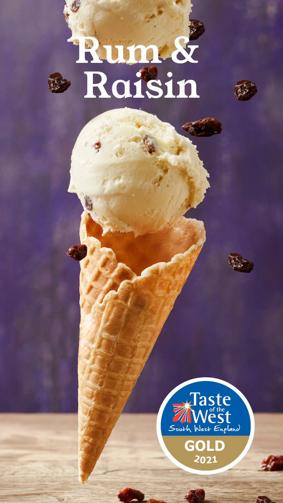 Close-up of a scoop of rum and raisin ice cream in a waffle cone, with raisins floating around, against a purple background, with a trophy badge at the bottom right corner.