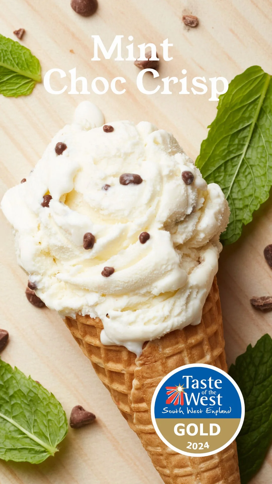 A scoop of vanilla ice cream with chocolate sprinkles in a waffle cone, garnished with mint leaves on a wooden surface.
