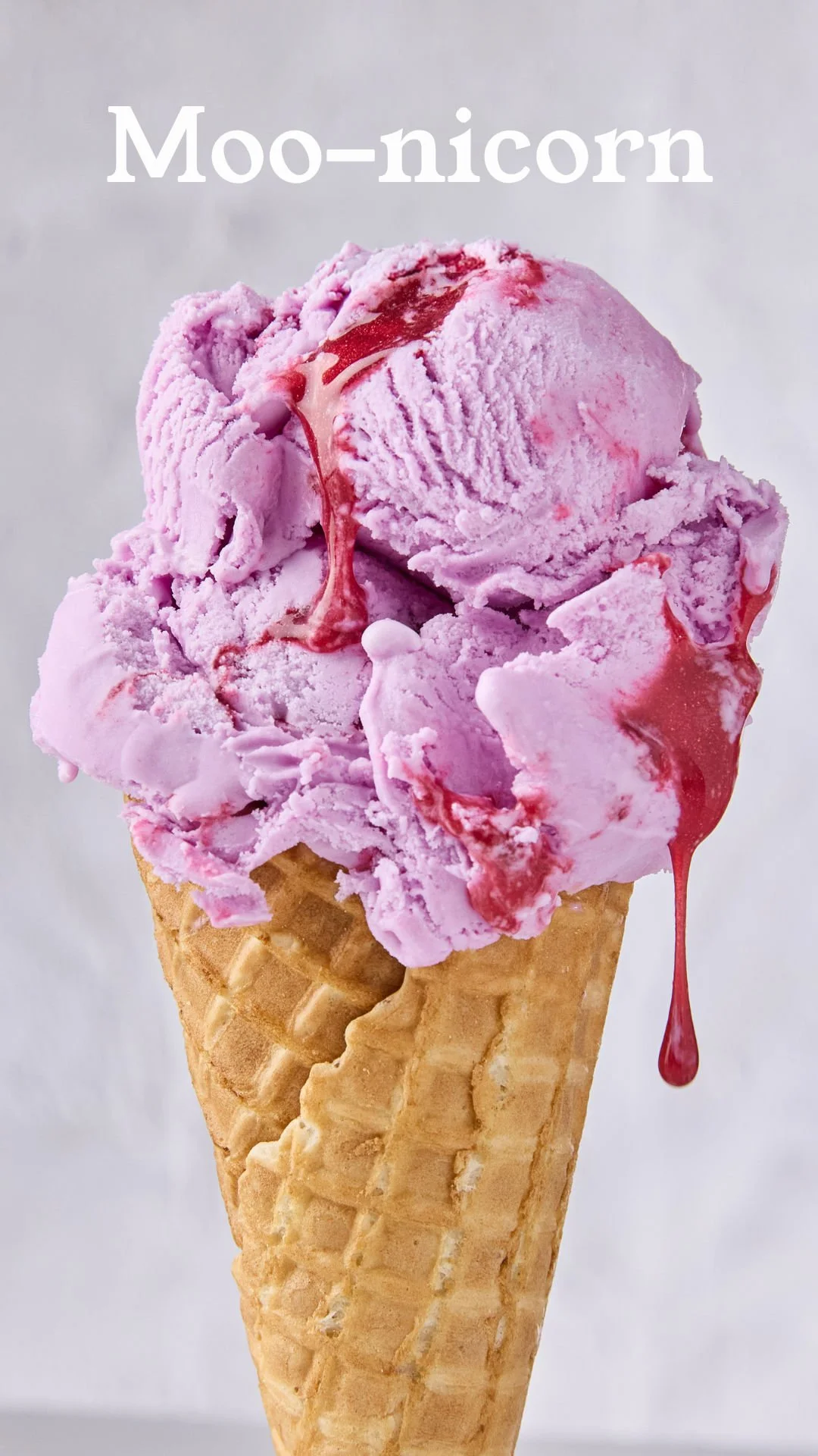 A cone of pink ice cream with red syrup drizzled on top, labeled 'Moo-nicorn'.