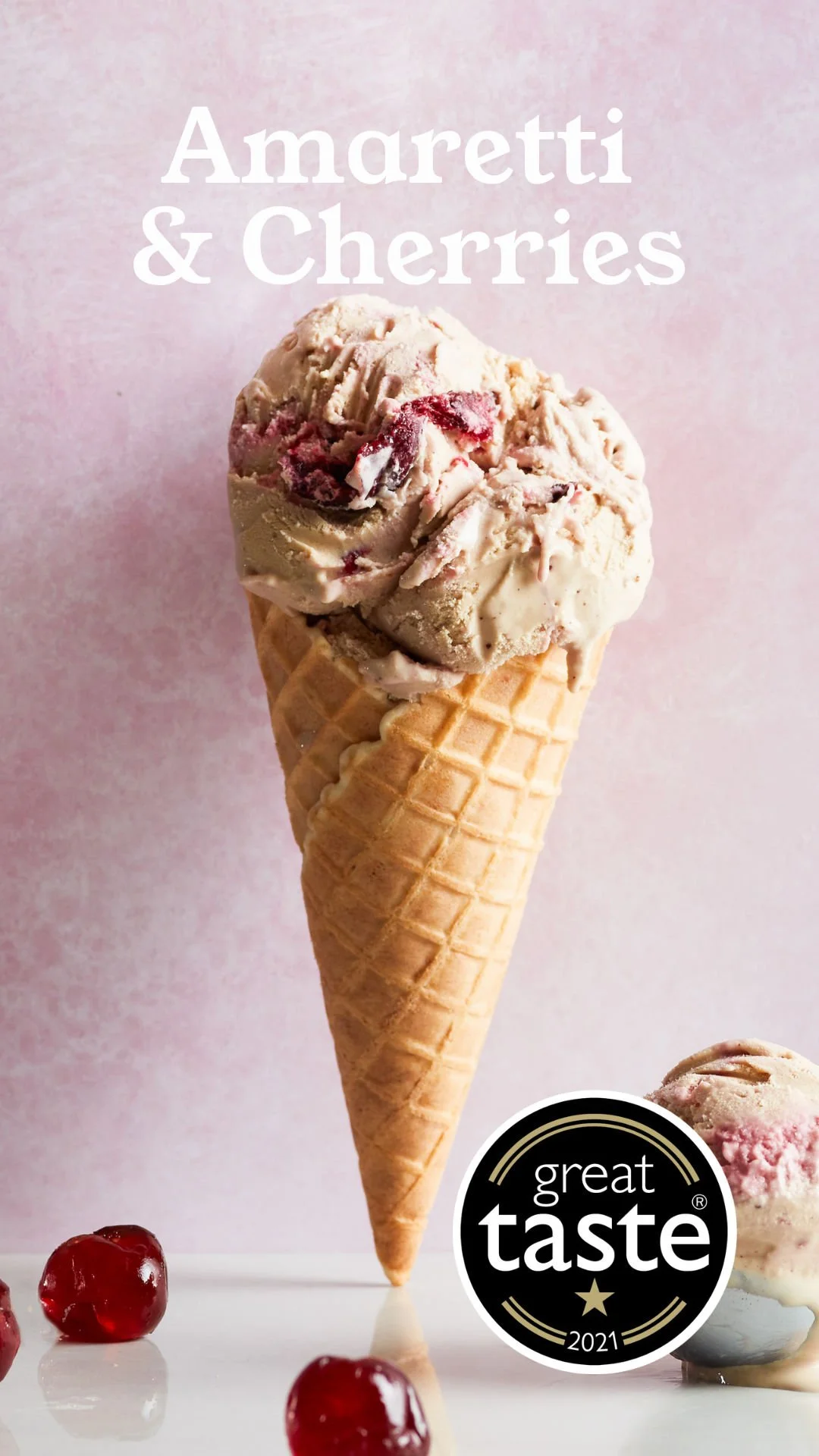 Ice cream cone with Amaretti and cherries, and cherries on the surface, with a pink background and a 'great taste 2021' award badge.