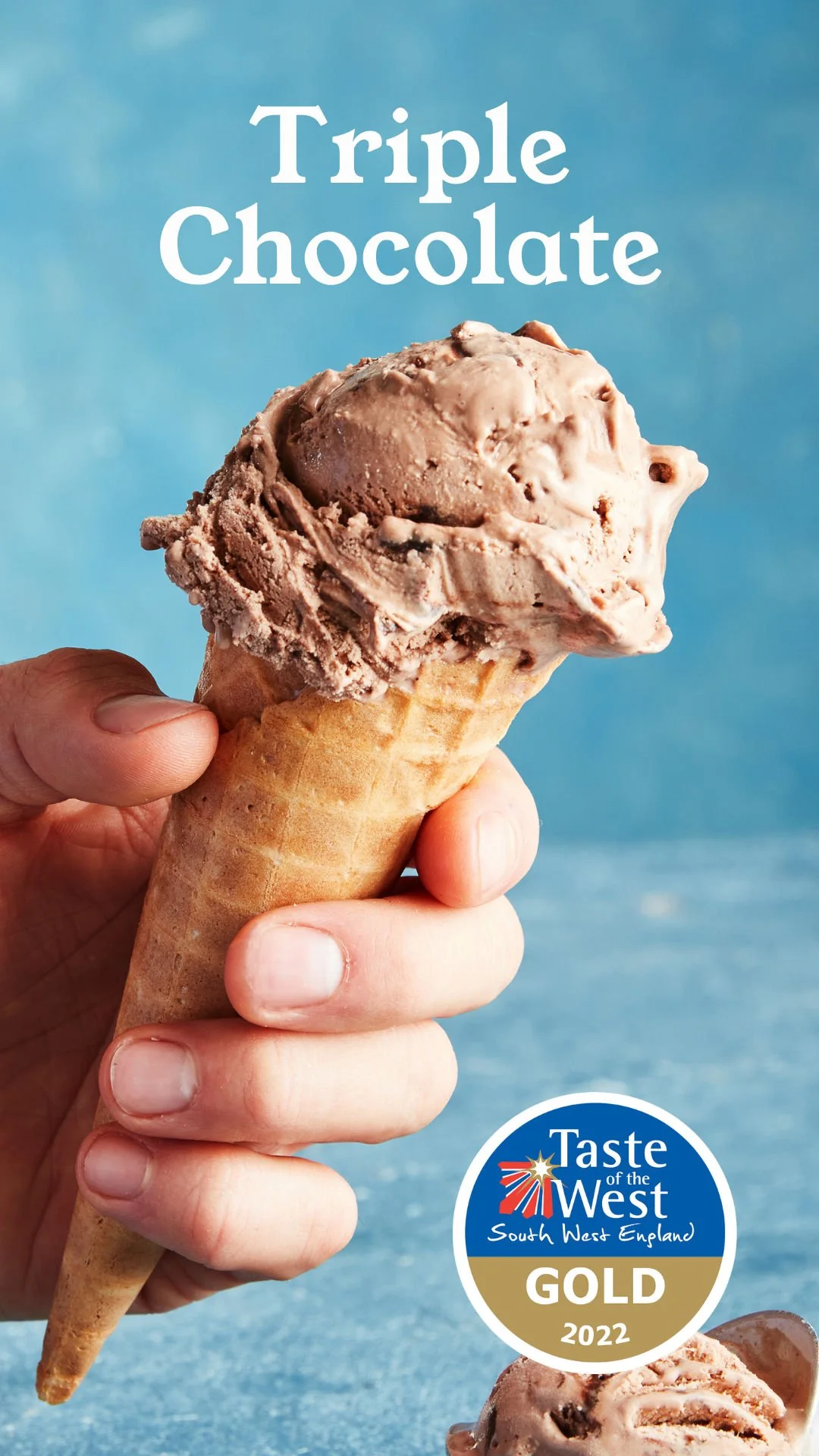 A hand holding an ice cream cone with chocolate ice cream, against a blue background with the text "Triple Chocolate" at the top and a gold and white circle at the bottom that says "Taste of the West South West England GOld 2022."