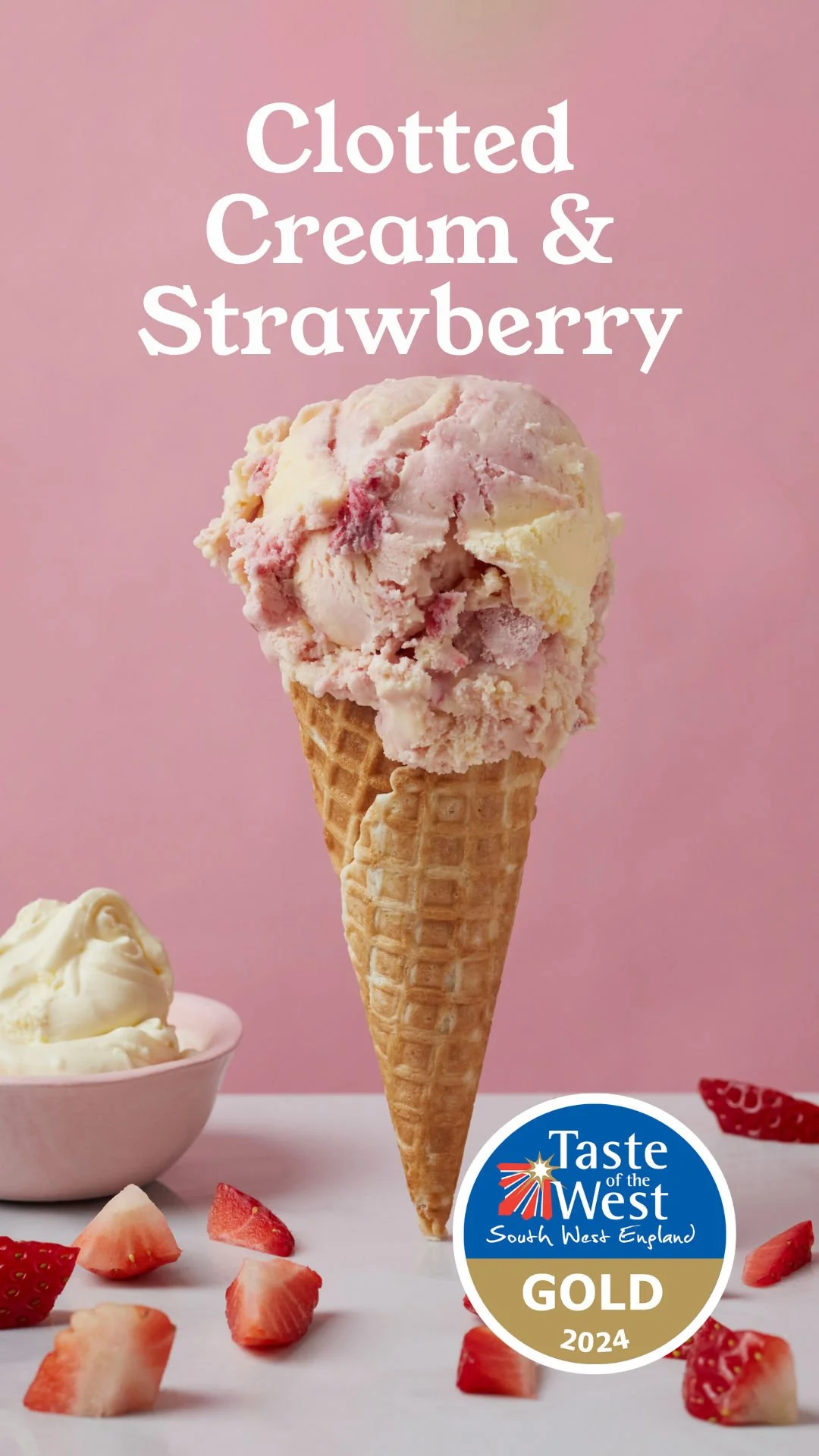 Close-up of a pink and white strawberry ice cream scoop in a waffle cone, with a bowl of ice cream, strawberries, and a pink background. Contains a label that reads "Taste of the West South West England G0LD 2024."