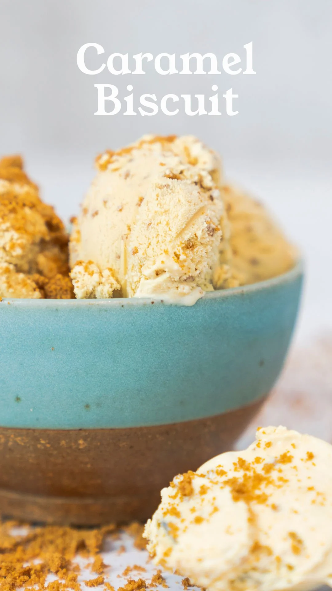 A bowl of caramel biscuit ice cream with crumbs and a scoop of ice cream outside the bowl.
