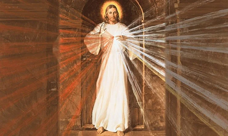 Painting of Jesus Christ with rays of light emanating from his heart, standing in an arched doorway with wooden walls.