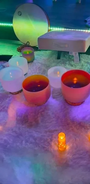 Colorful candles and decorative items on a soft, fluffy surface with ambient lighting in the background.