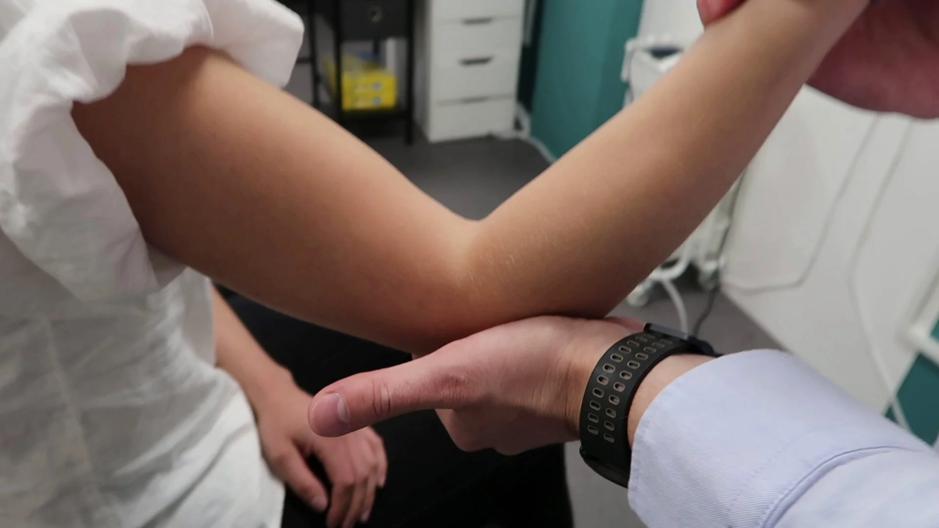 A close-up of a person's arm being examined by a healthcare professional in a clinical setting.