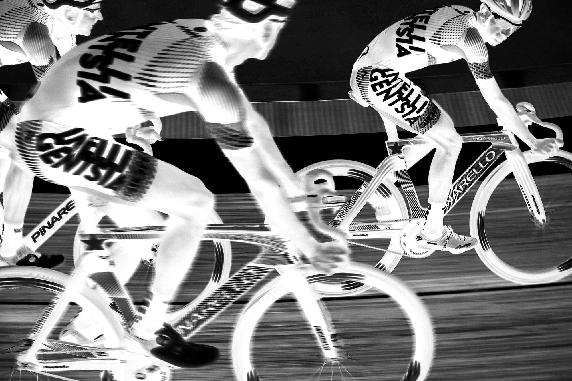Infrared image of three cyclists racing on a track, wearing helmets and sports gear with the word 'FISHER' visible on their clothing.