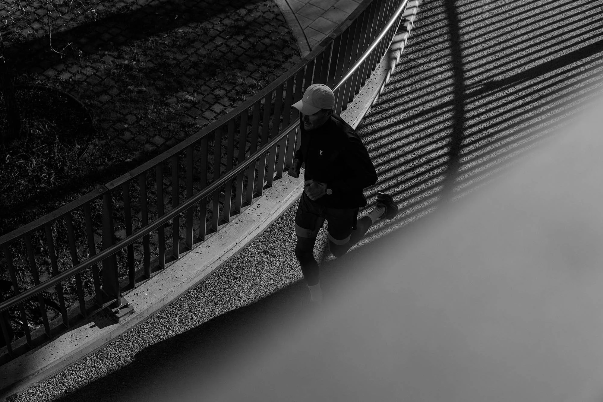 Jan Frodeno jogging on a bridge in Munich at night with shadows cast from the bridge's railing.