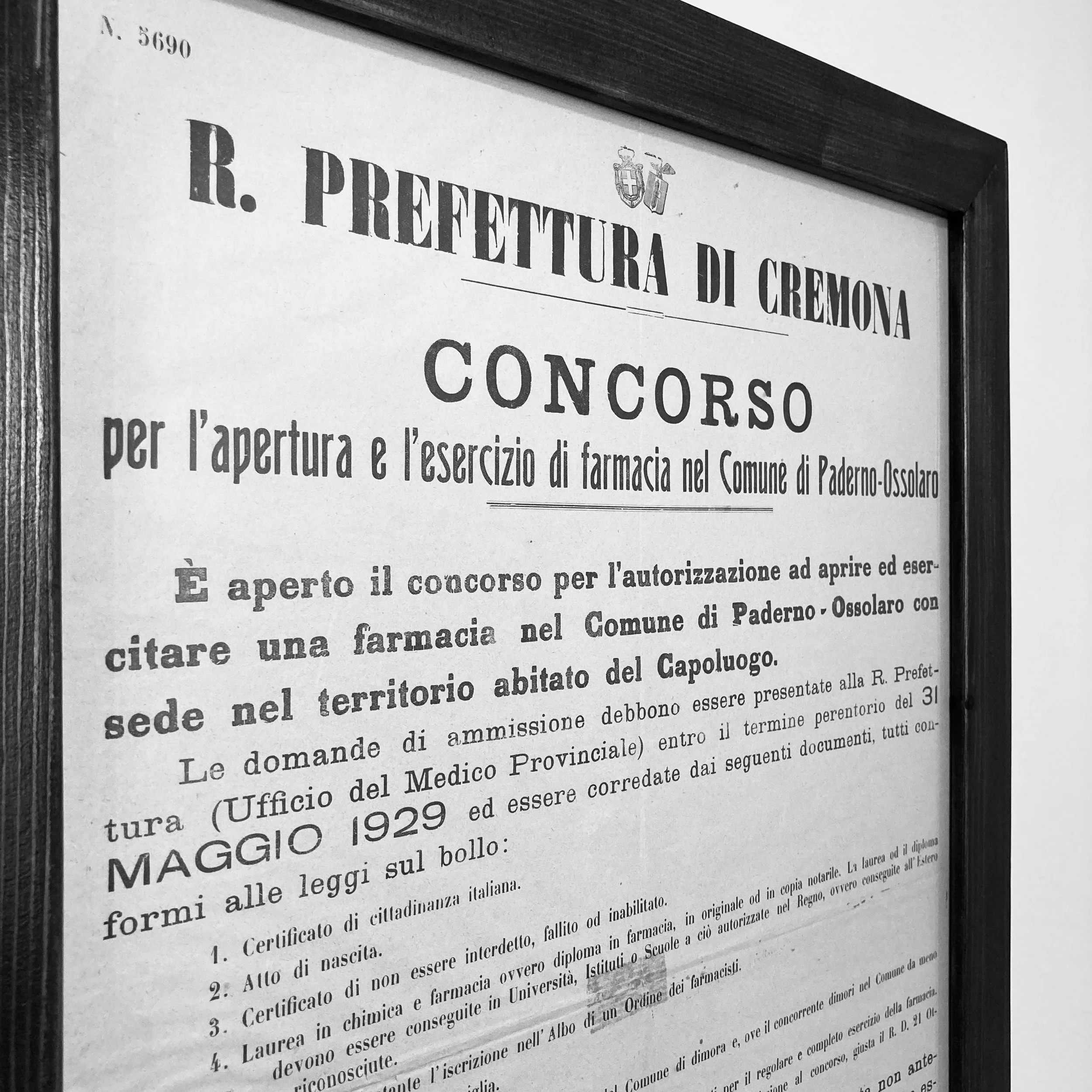 Copertura di un avviso in bianco e nero della Prefettura di Cremona riguardante un concorso per l'apertura di una farmacia nel comune di Paderno-Ossolaro, con informazioni sui requisiti e le modalità di presentazione delle domande, datato maggio 1929