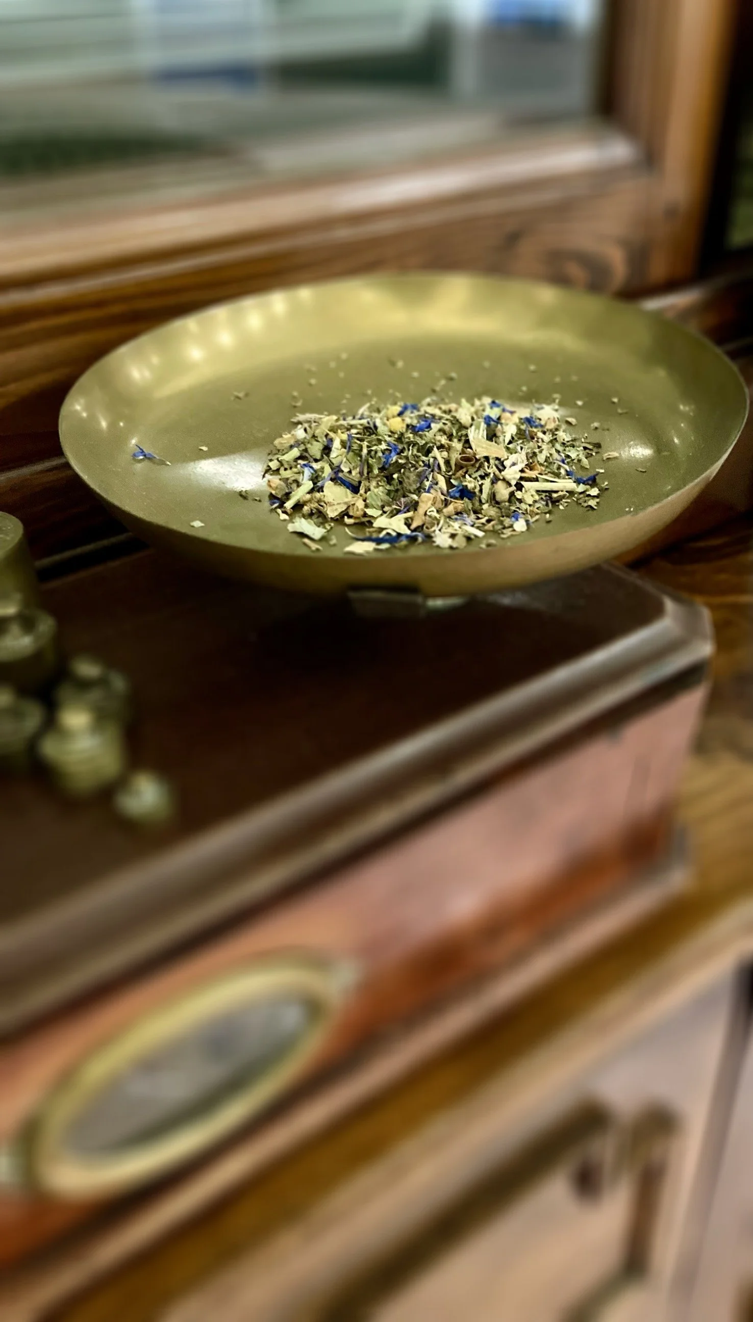 Erbe secco in una ciotola verde satinata su un mobile di legno.