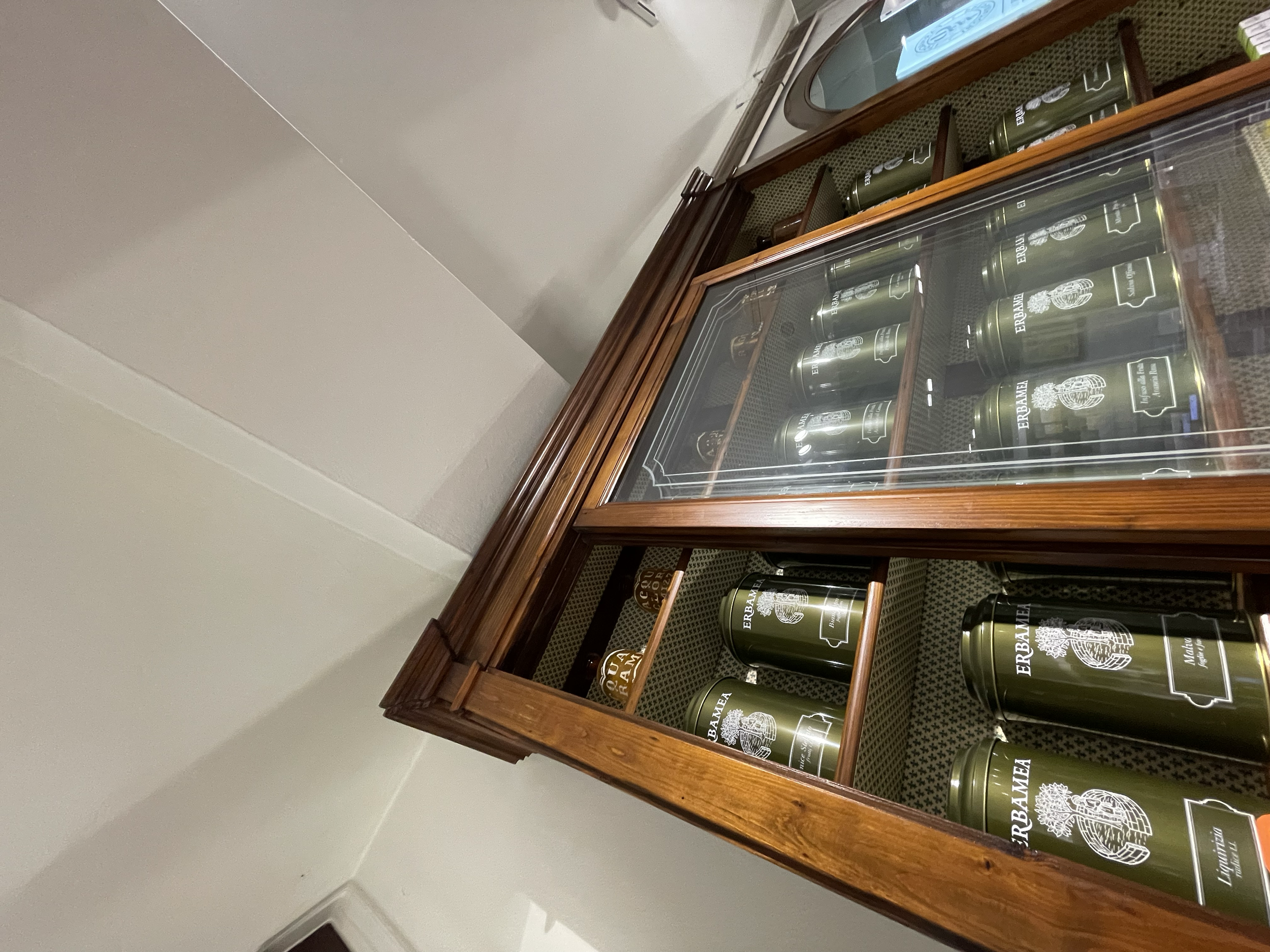 Una vetrina in legno con bottiglie di vino Erbamea esposte all'interno.