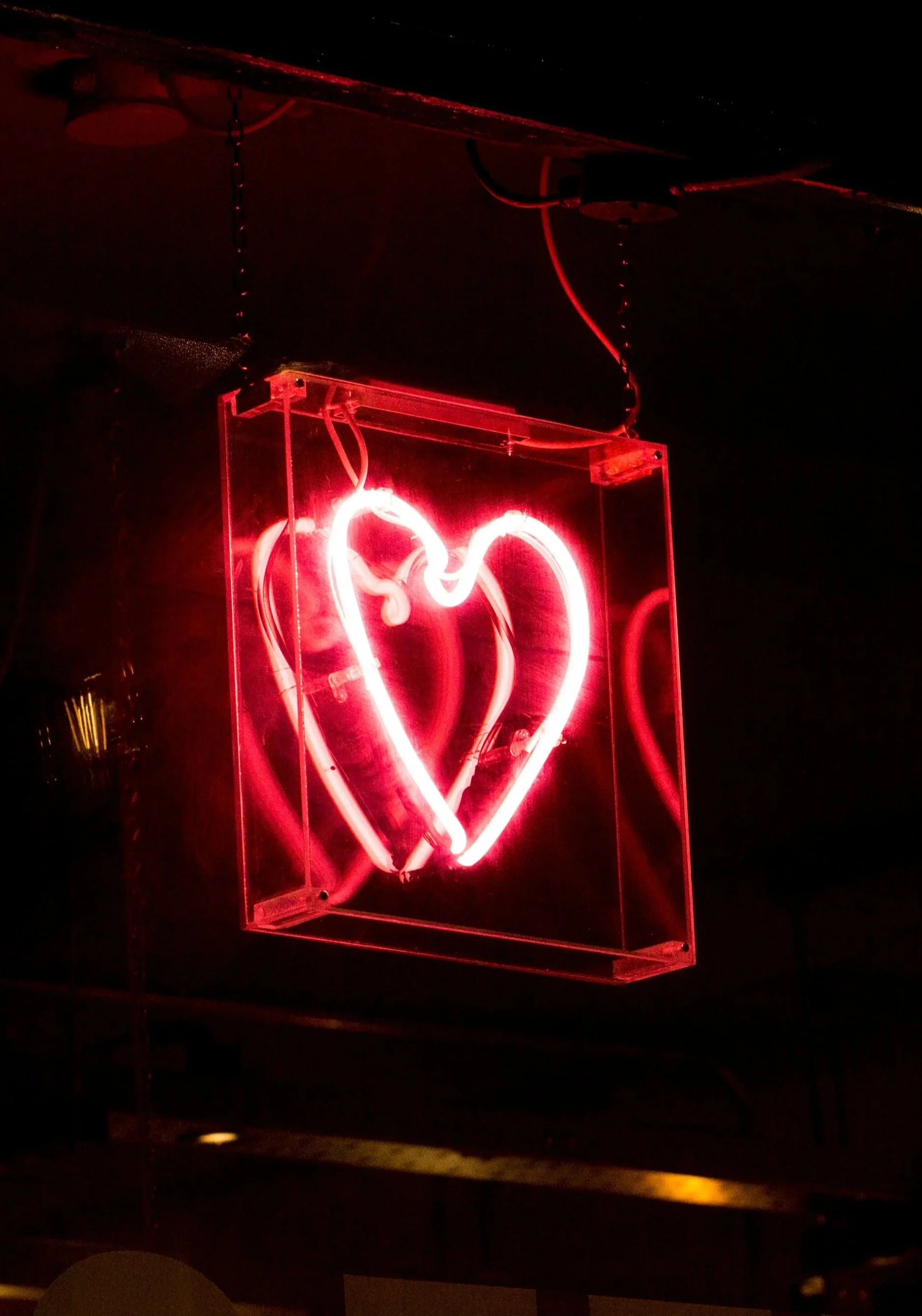 Segno luminoso a forma di cuore rosso sospeso in una teca di vetro