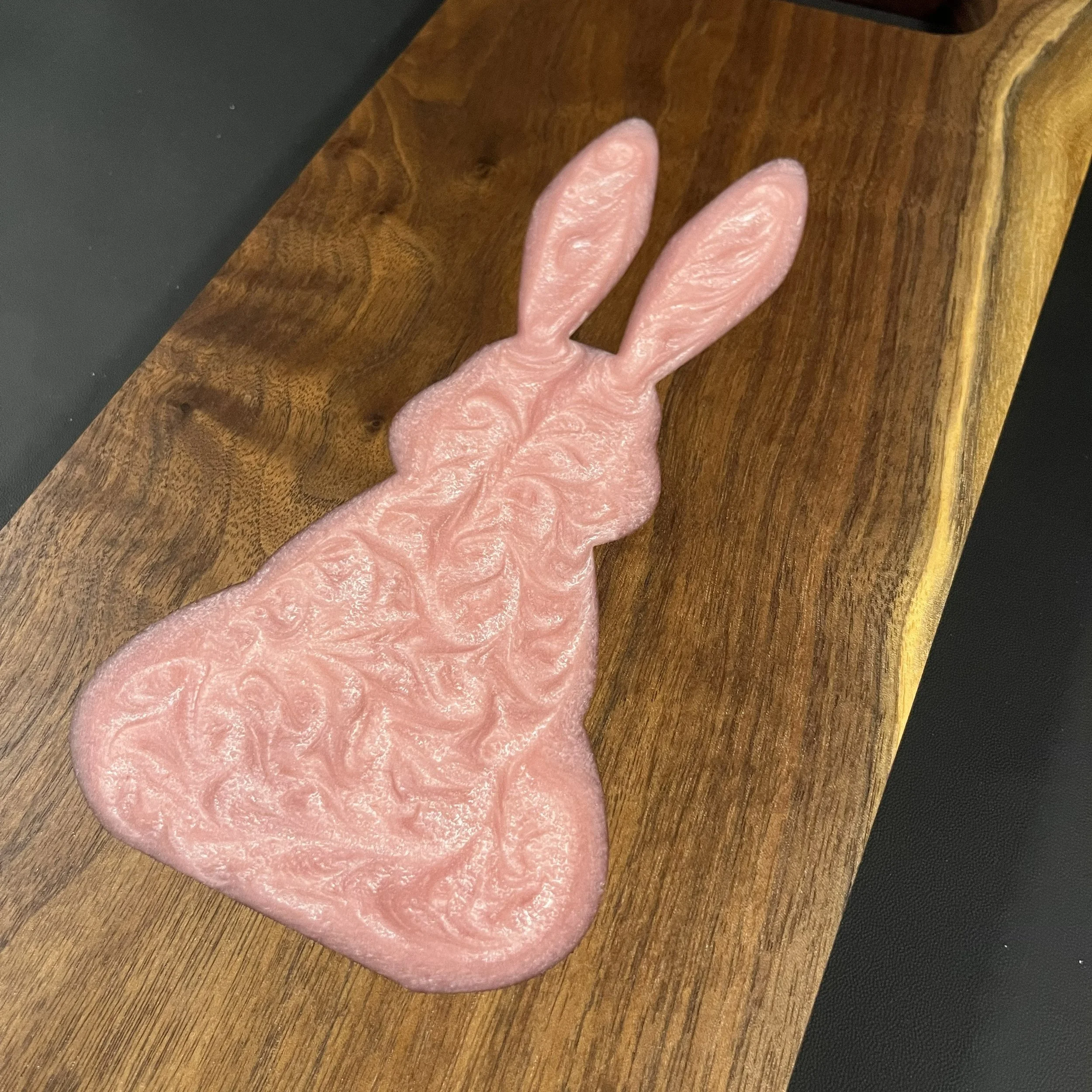 Pink swirl epoxy Easter bunny on walnut with a streak of sap wood.