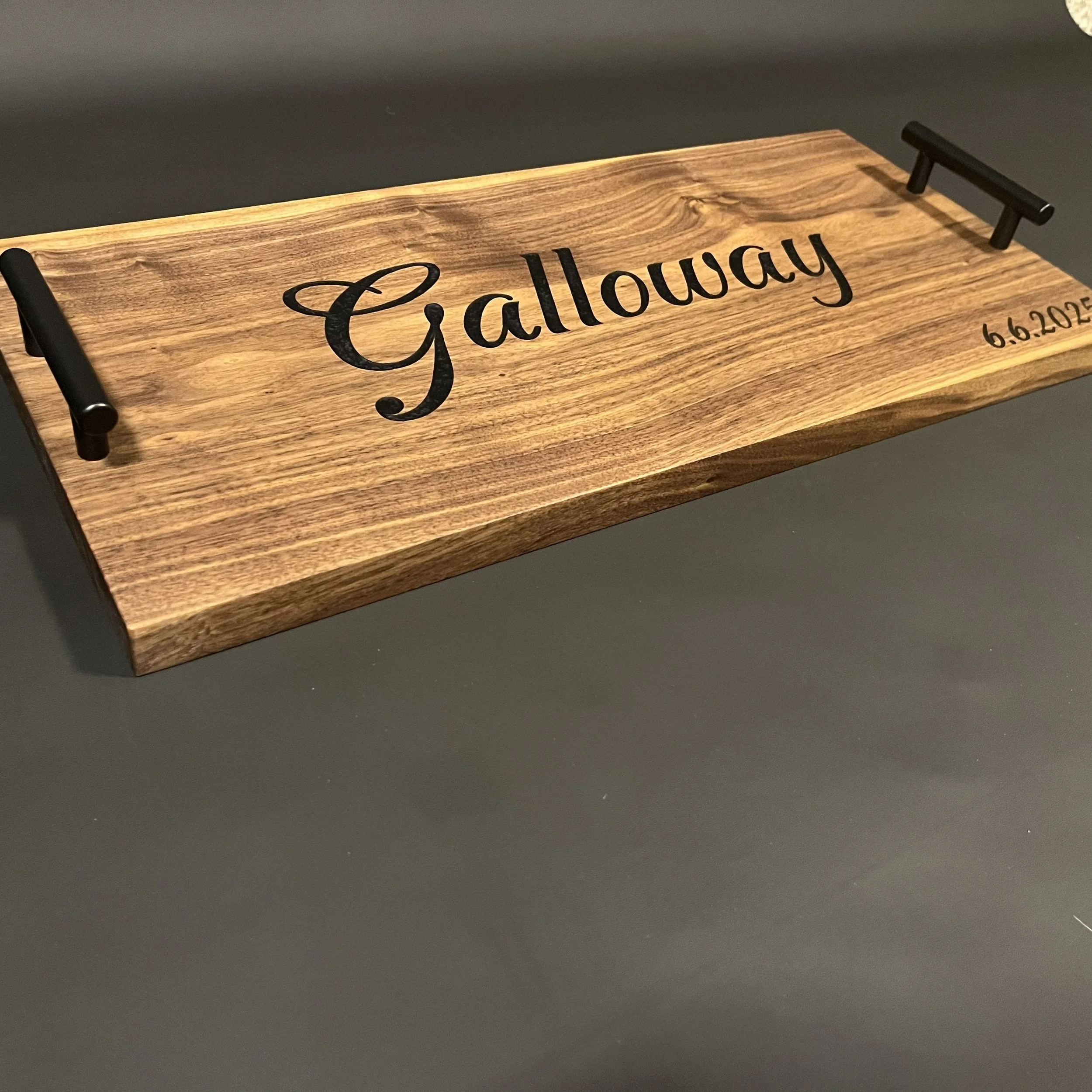 Wooden display plaque with black handles and the word 'Galloway' engraved in black script, along with the date '6.6.2022' engraved in smaller print.