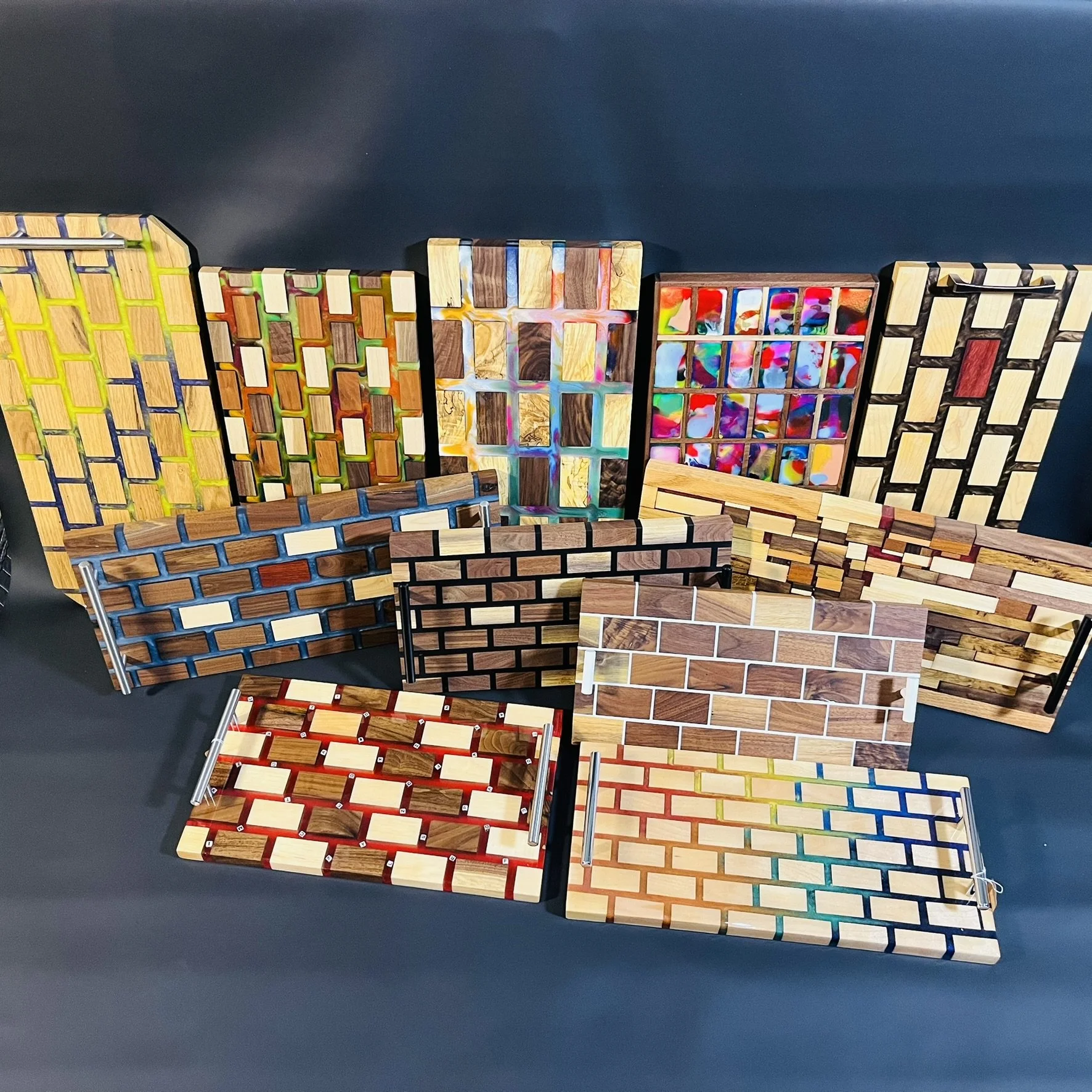 Multiple decorative miniature brick wall plaques with various colors and patterns, arranged on a black surface.