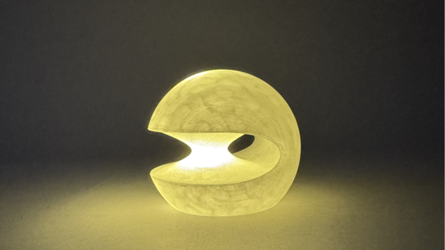 Lampshade with a Pac-Man shape, glowing on a table.