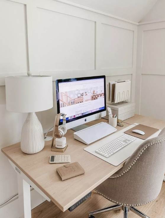 home office desk with a computer, lamp, headphones, calculator, wallet, notepad, and chair in a white-walled room