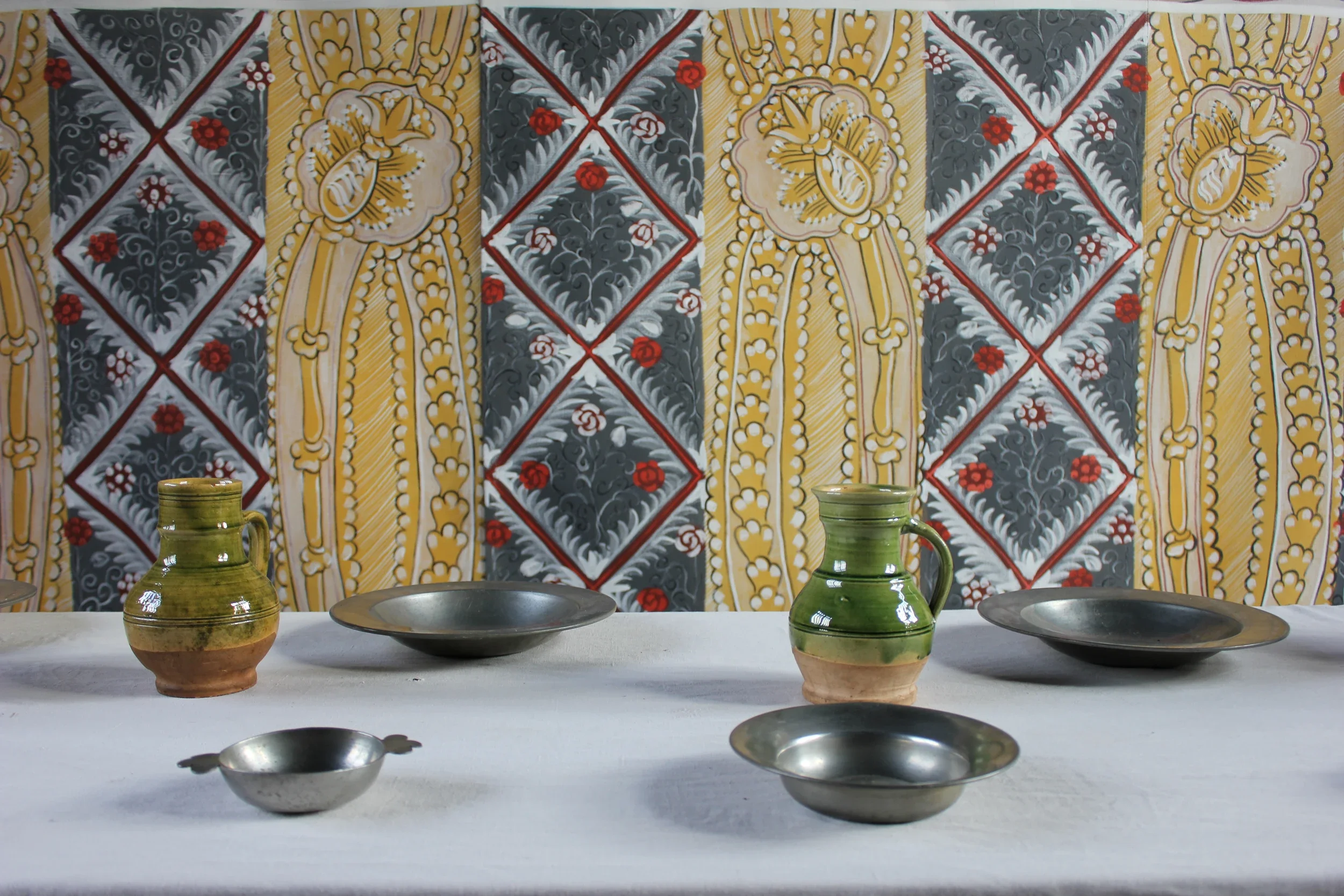A close-up of Melissa White's Bayleaf Tudor cloth with a dressed Tudor table pictured in front of it.