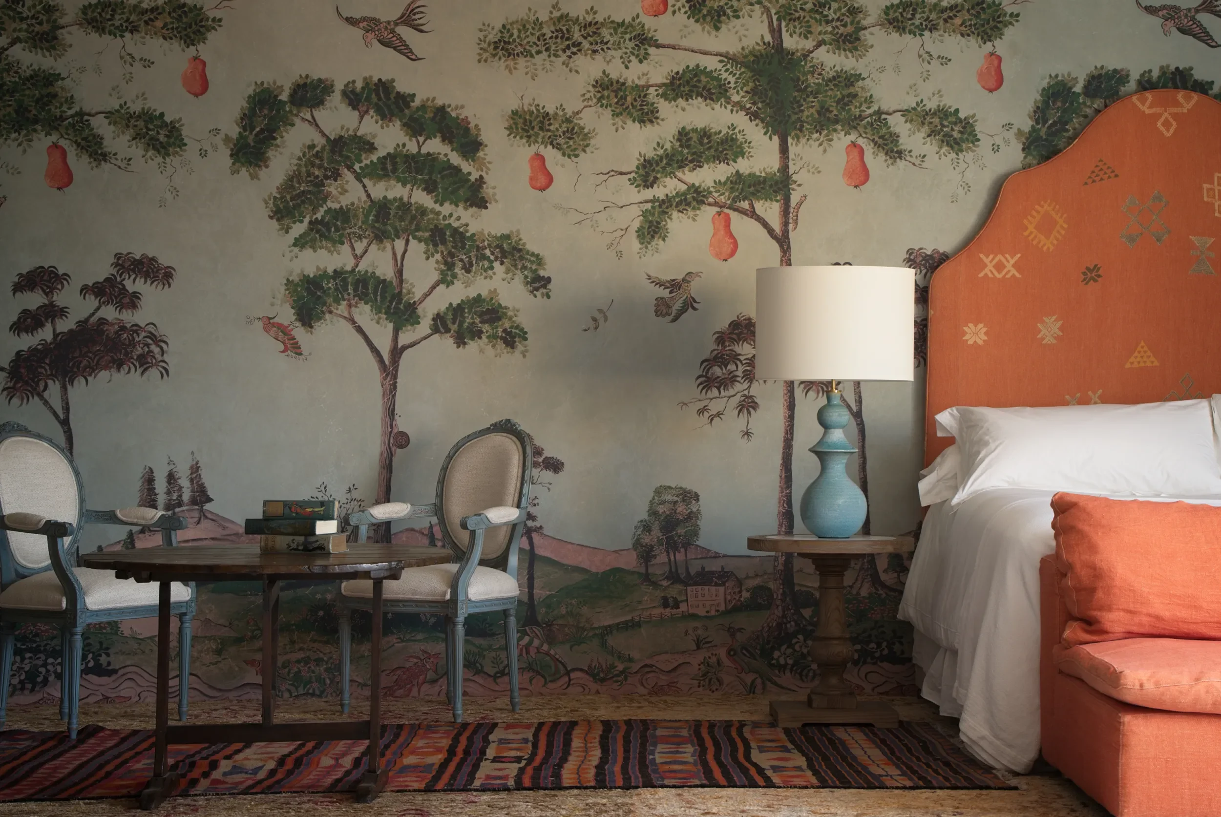 Photo shows Melissa White's Mythical Land wallpaper with Kit Kemp for Andrew Martin in a bedroom or hotel setting.