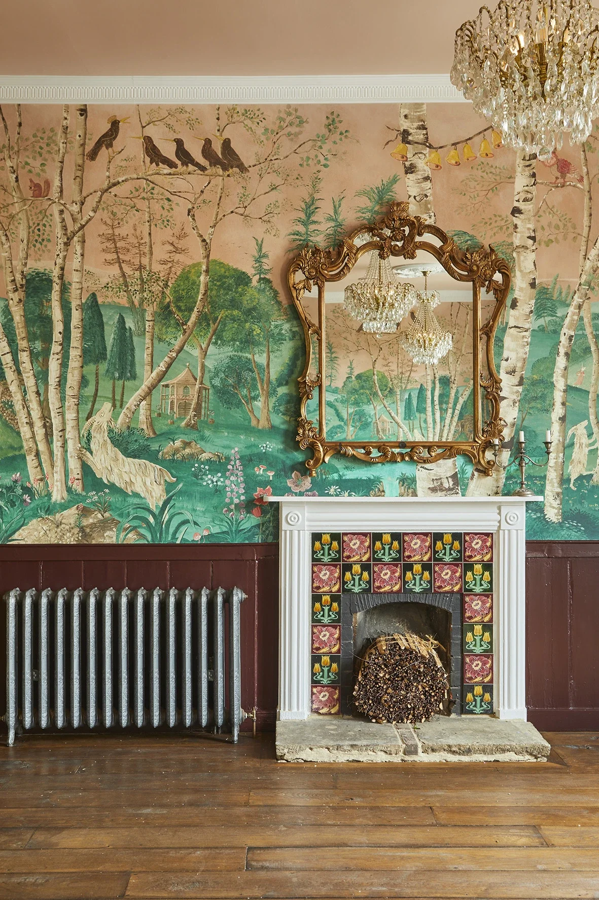 The Big Room at The Bell in Ticehurst, East Sussex, showing the bespoke scenic wallpaper by Melissa White, 2020. Hand-painted woodland landscape with silver birch trees. Photo shows fireplace with mirror.