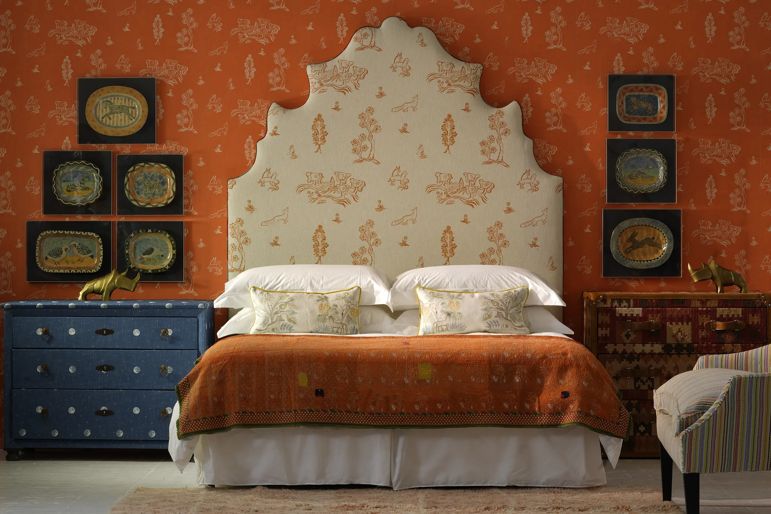 Friendly Folk by Melissa White together with Kit Kemp. The wallpaper is shown in orange with a contrasting white and orange headboard in the same colour.