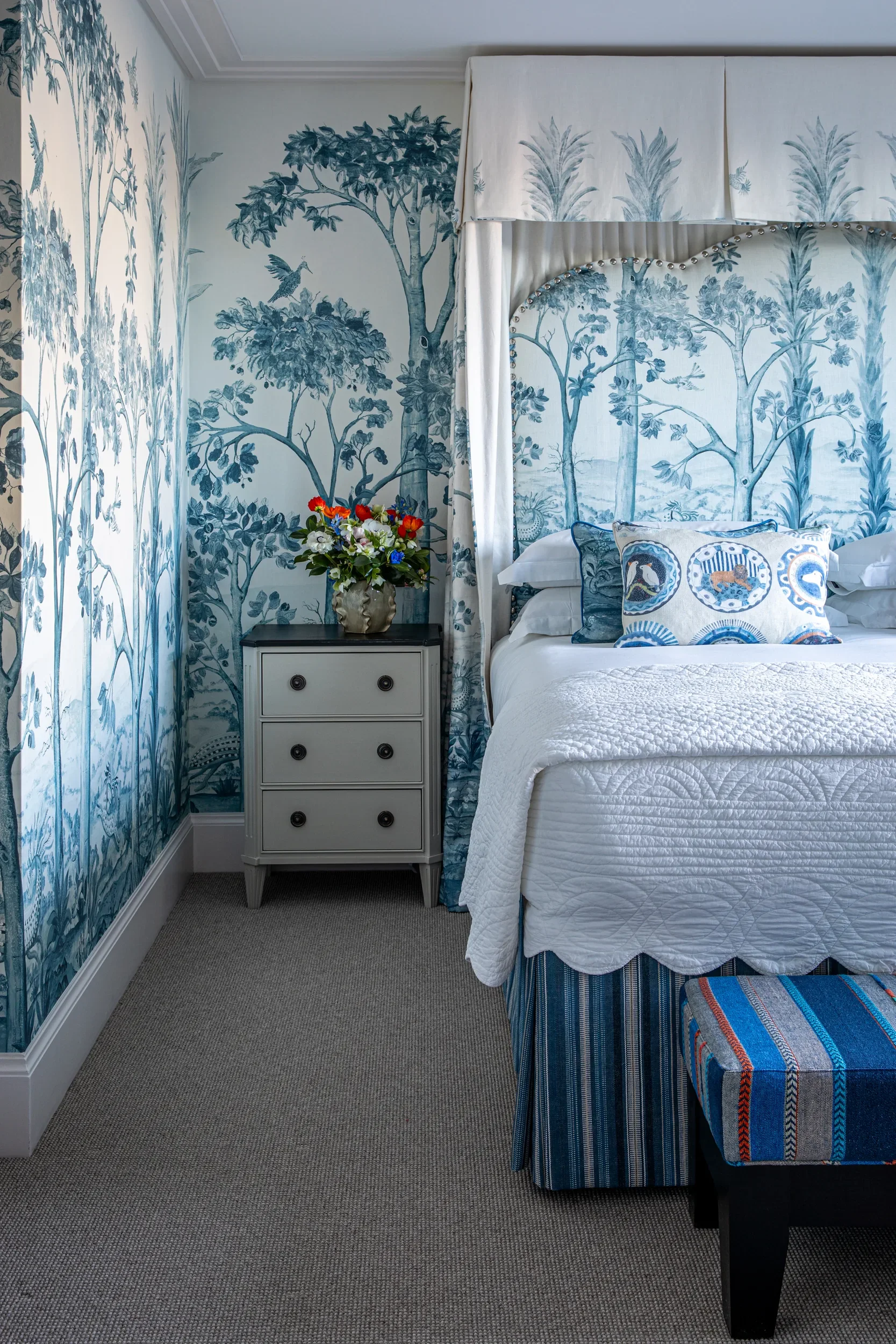 Tall Trees wallpaper by Melissa White for GP&J Baker, Kit Kemp Wallpaper collection. Staged in a bedroom with armchair, flowers and smartly presented bed.