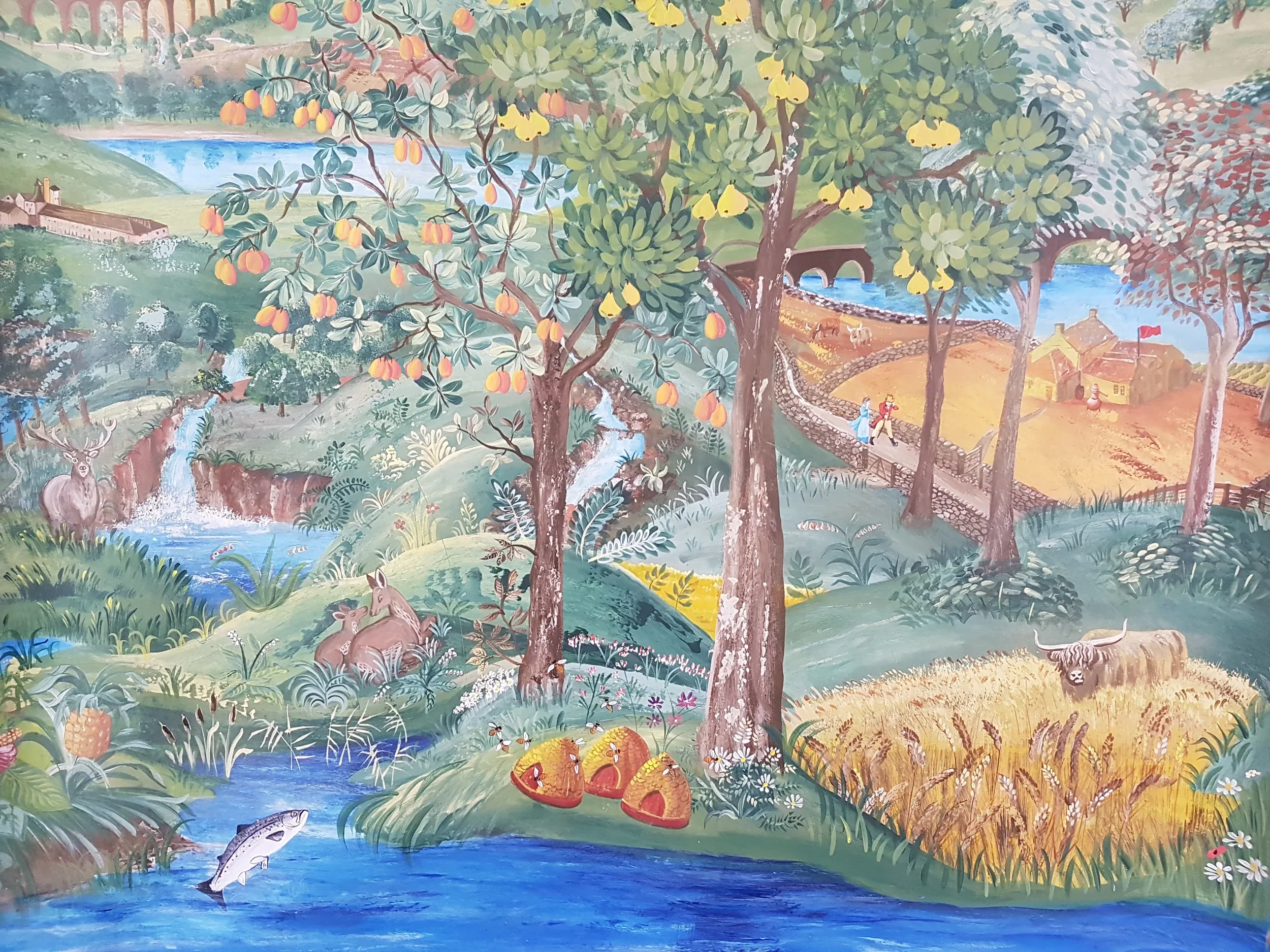 A colorful mural depicting a countryside scene with streams, trees bearing fruit, a stone bridge, a deer, fish in a river, and people walking near a small house with a red flag.