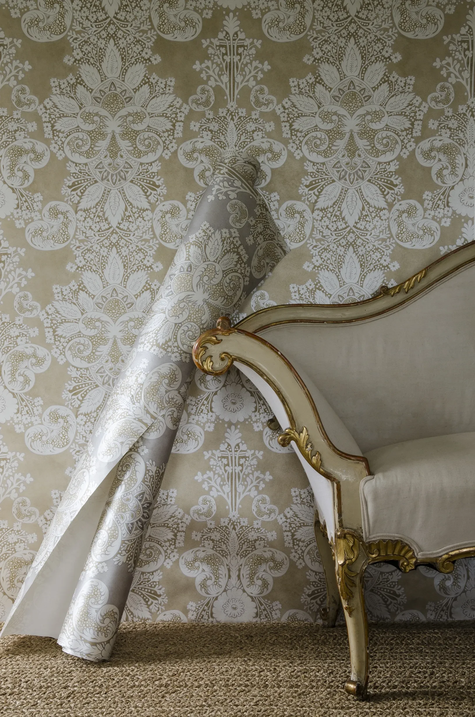 Rococo fabric by Melissa White for Lewis & Wood, shown alongside an ornamental chair with a rolled up wallpaper panel leaning against it.
