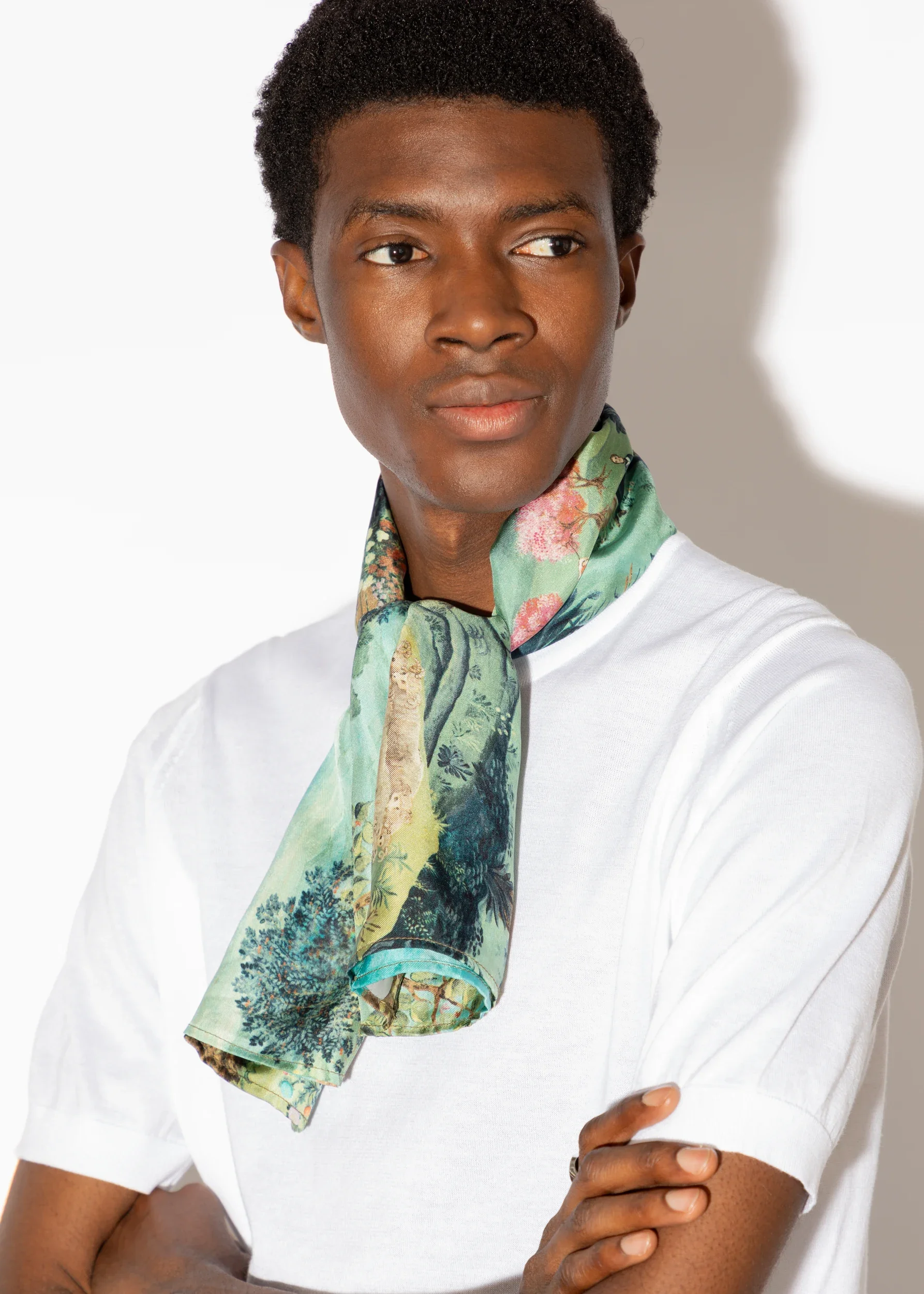 Close-up of a person with deep skin wearing a white T-shirt and silk scarf from Melissa White's collaboration with John Smedley on the occasion of their 240th anniversary.