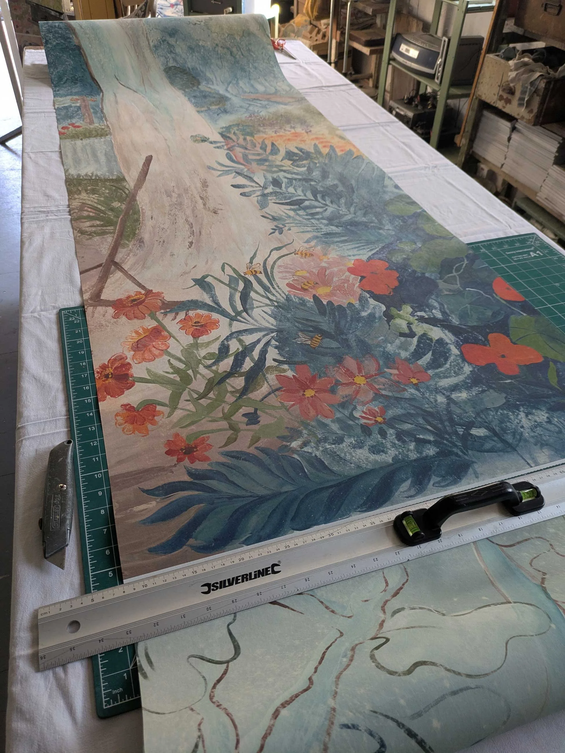 Melissa White’s studio featuring the original mural artwork on the walls and a hand-painted panel on the table.