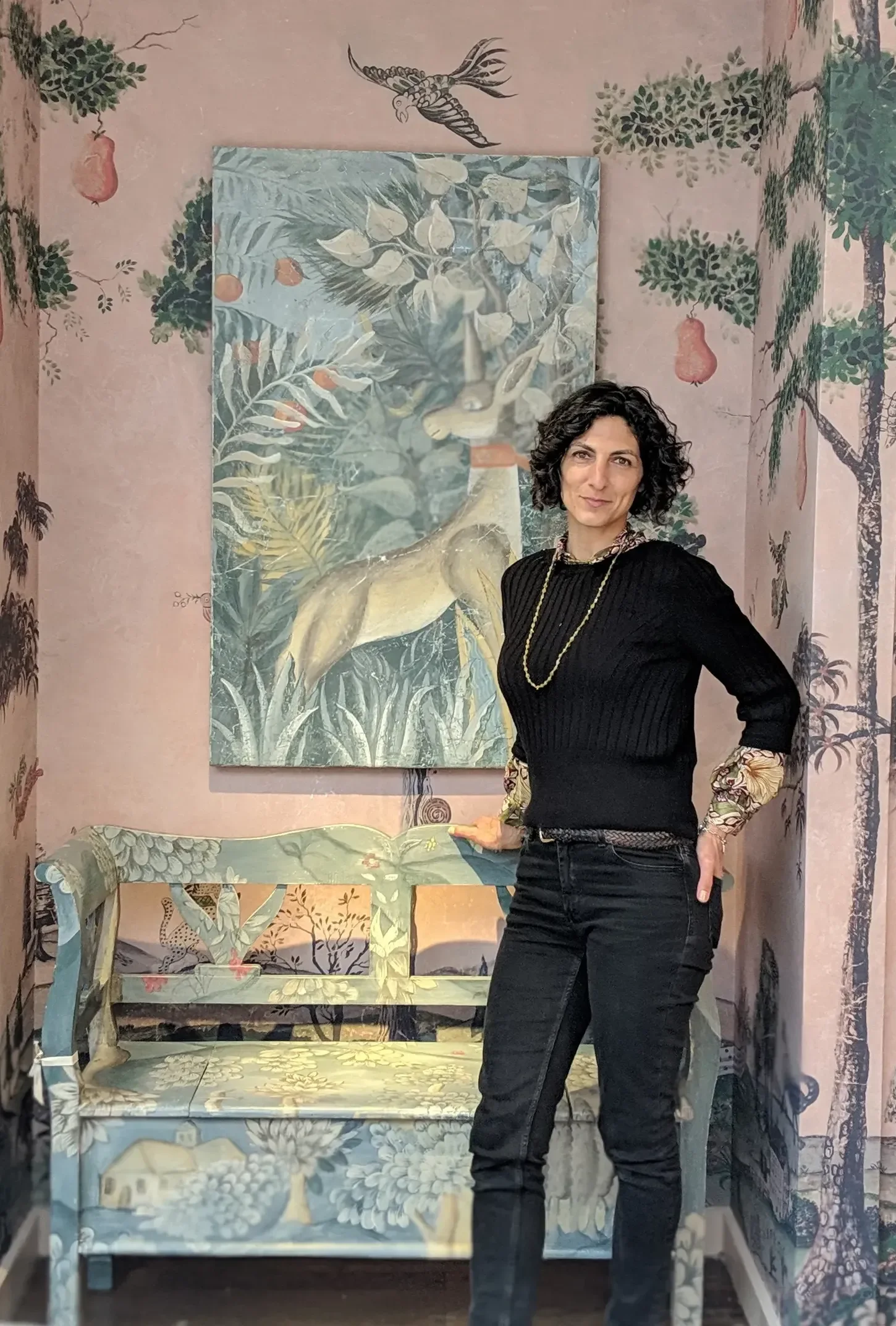 Melissa White at Kit Kemp's Drawing Room installation, Bergdorf Goodman, New York, 2019, standing beside her hand-painted verdure bench with fresco secco panels and Mythical Land mural visible behind her.