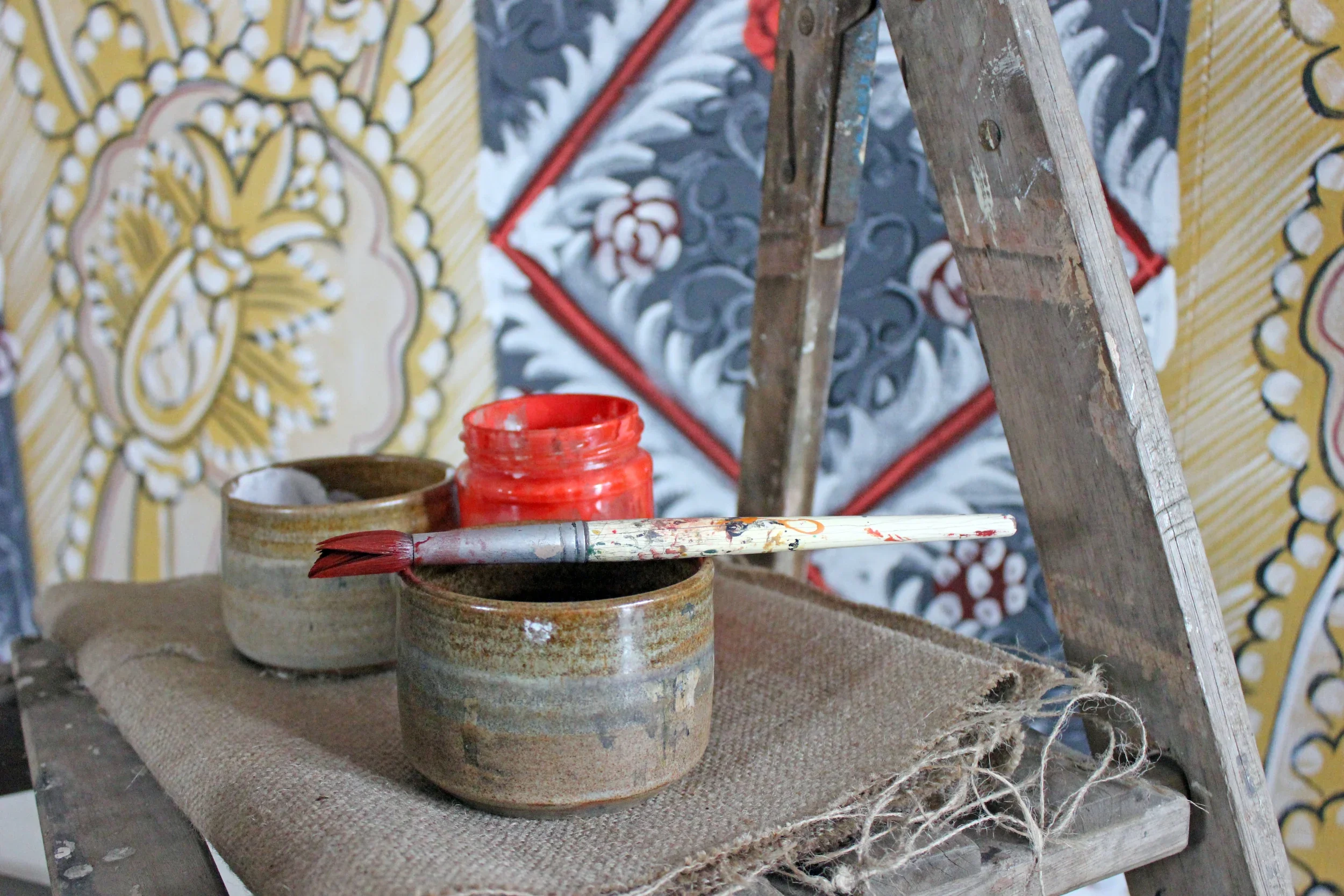 Close-up of Melissa White's paint and brushes in front of the Bayleaf cloth work in progress.