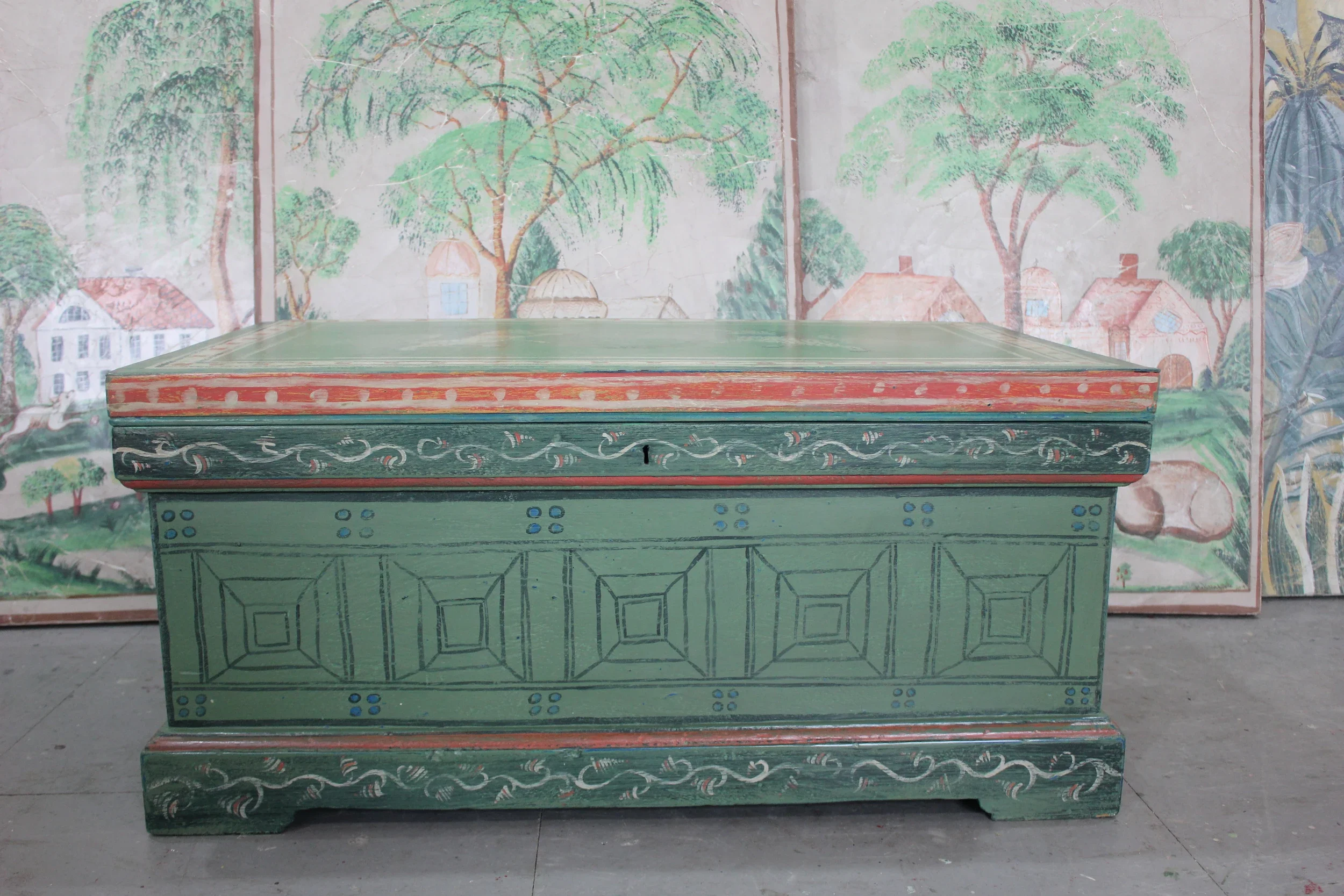 Hand-painted decorative chest by Melissa White, made for Kit Kemp's Drawing Room installation at Bergdorf Goodman, New York, 2019. Green ground with hand-painted unicorns and trompe l'oeil coffering, with Mythical Land mural visible behind.