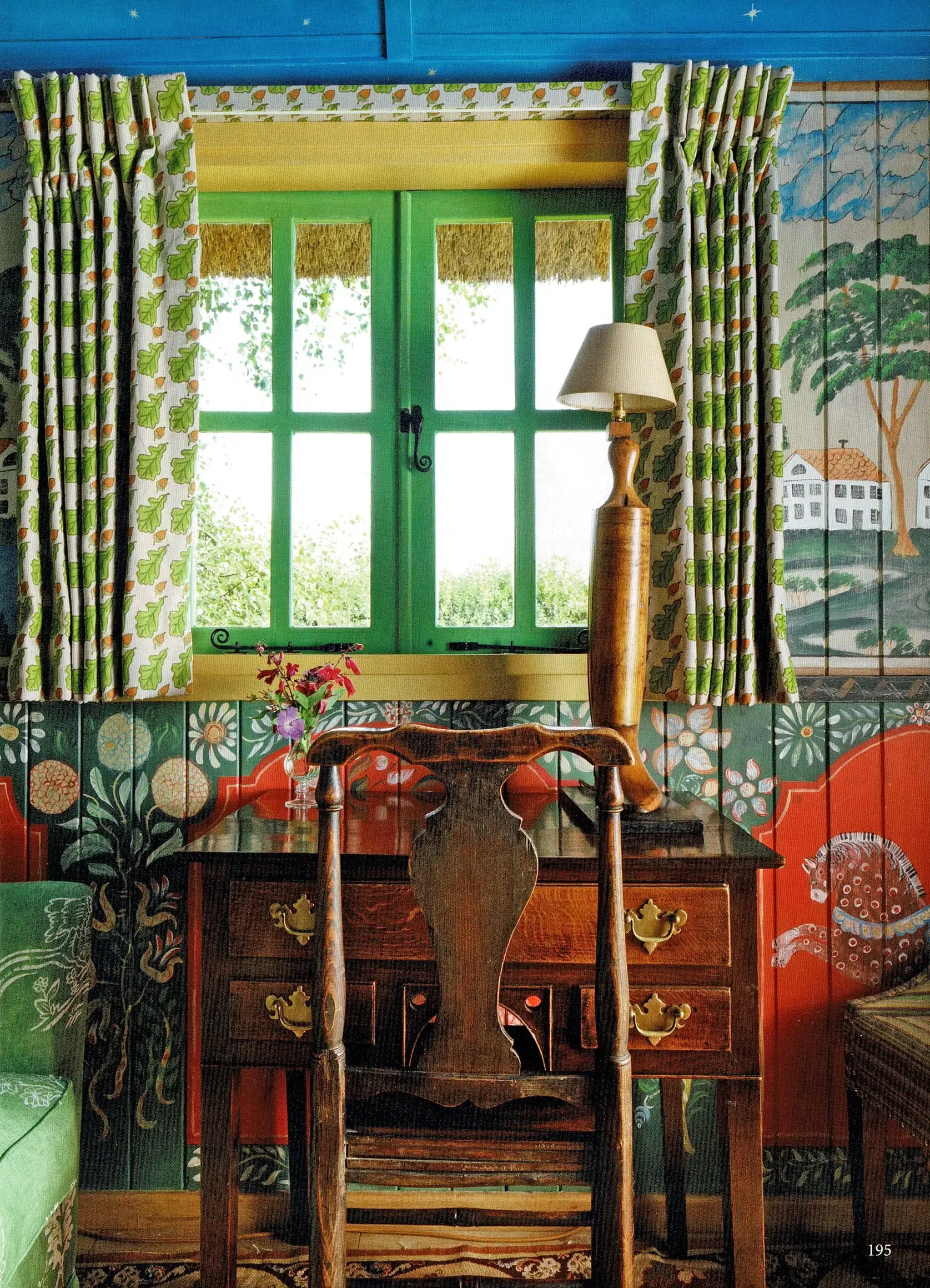Interior of Kit Kemp's Shepherd's Hut, New Forest, painted by Melissa White, 2019. Hand-painted folk art walls with an eighteenth-century country oak writing desk beneath the window. Photography by Simon Brown.