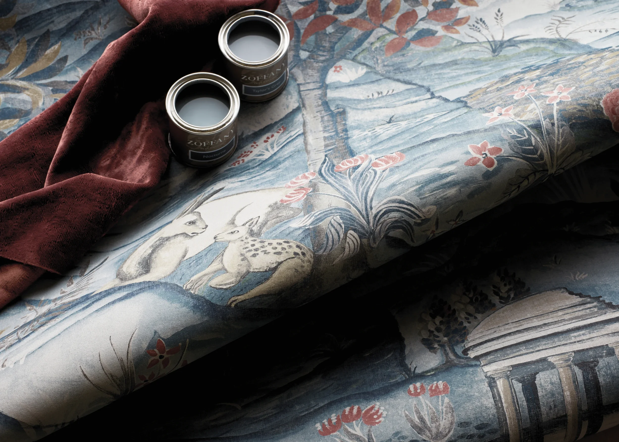 Two cans of Zofran medication resting on a fabric with a floral and animals print, accompanied by a piece of dark red cloth.