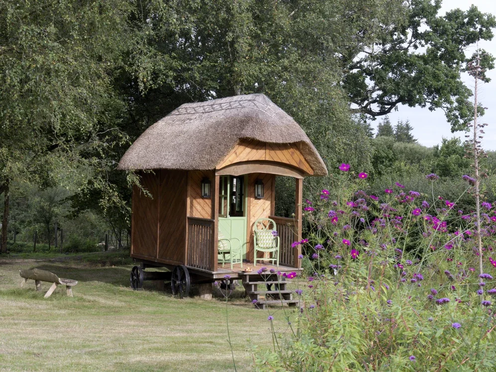 Exterior of Kit Kemp's Shepherd's Hut, New Forest, made by local forester John Harman. Oak structure on wheels with thatched roof, interior painted by Melissa White, 2019.