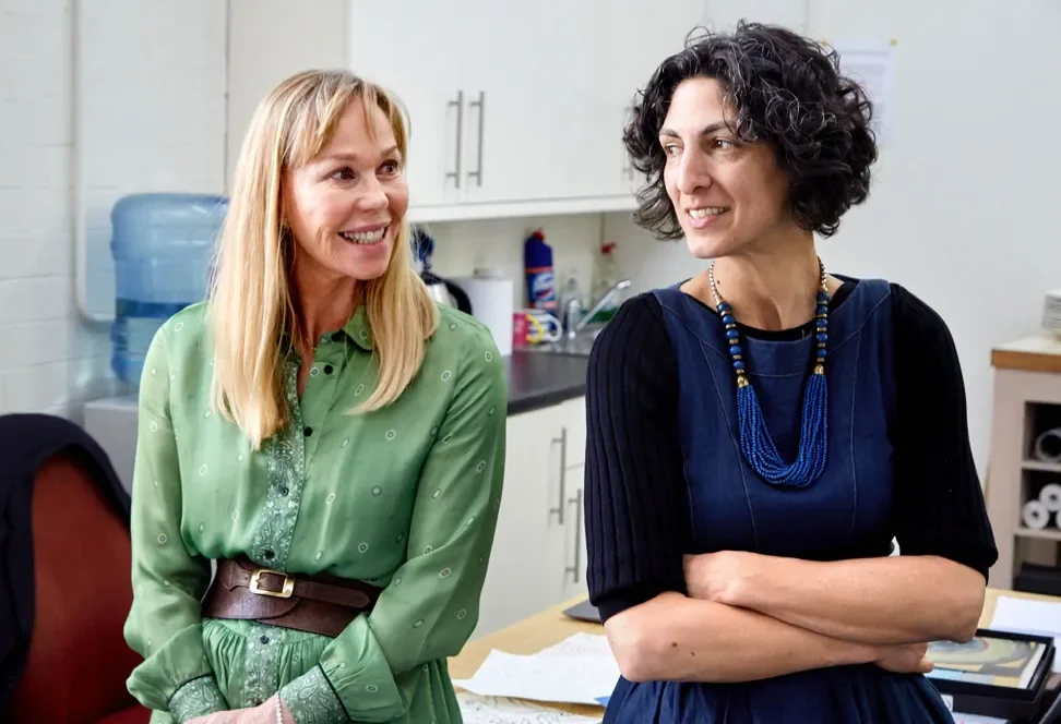 Kit Kemp and Melissa White are sitting next to each other in an office kitchen. They are smiling and chatting.