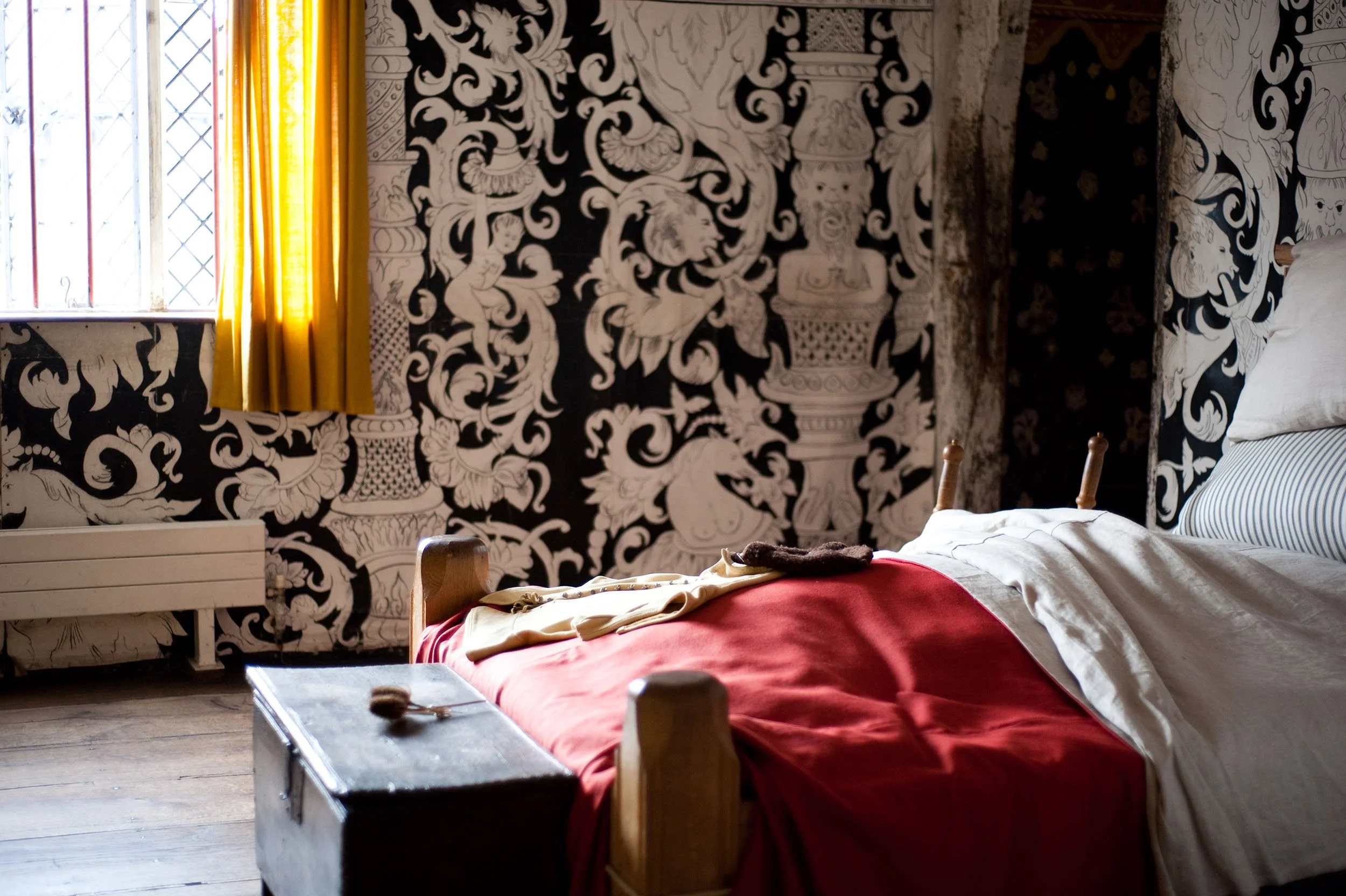 Painted cloths by Melissa White at Shakespeare's Birthplace Museum, Stratford-upon-Avon, 2000. Floor-to-ceiling Elizabethan black-and-white grotesque wall paintings in rabbit-skin glue and earth pigments, shown in a period bedroom setting.