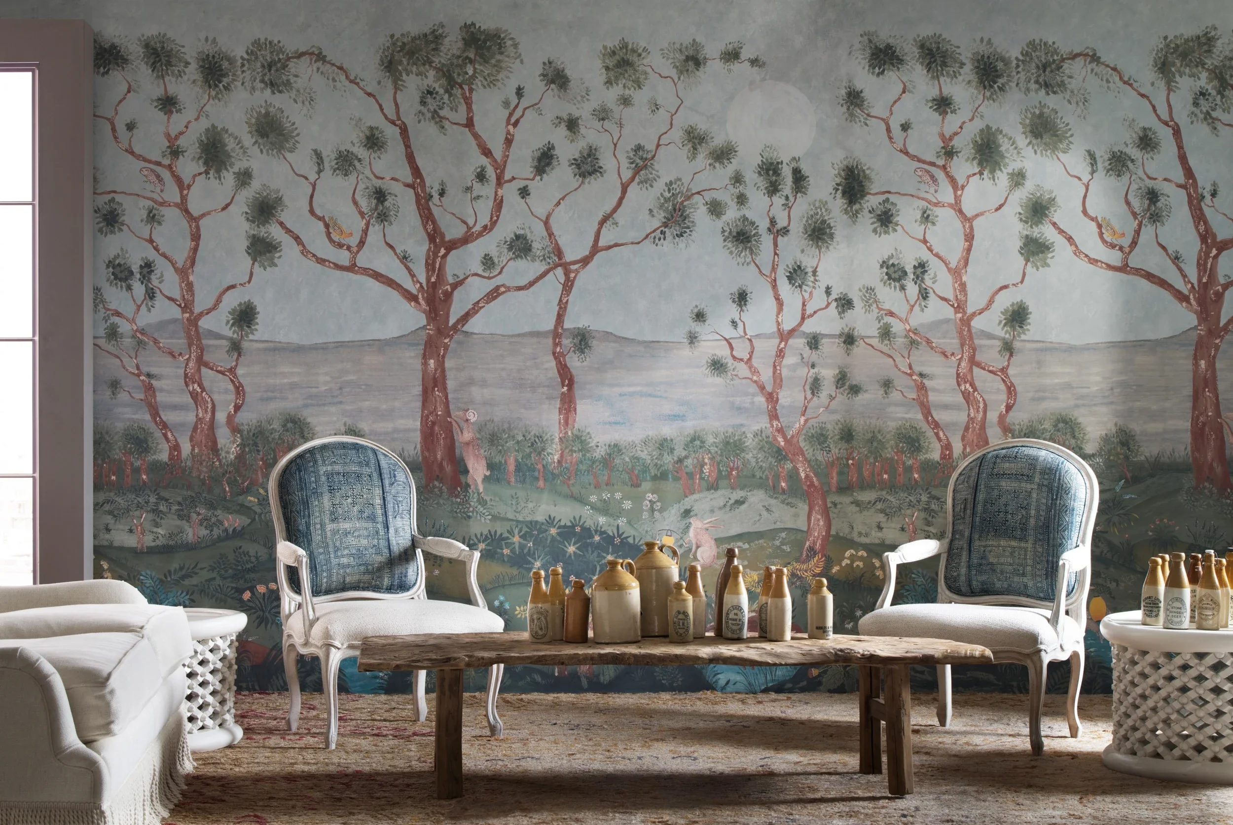 Melissa White's Lantern Parade wallpaper with Kit Kemp for Andrew Martin is pictured with a staged interiro - 2 armchairs, some rustic furniture.