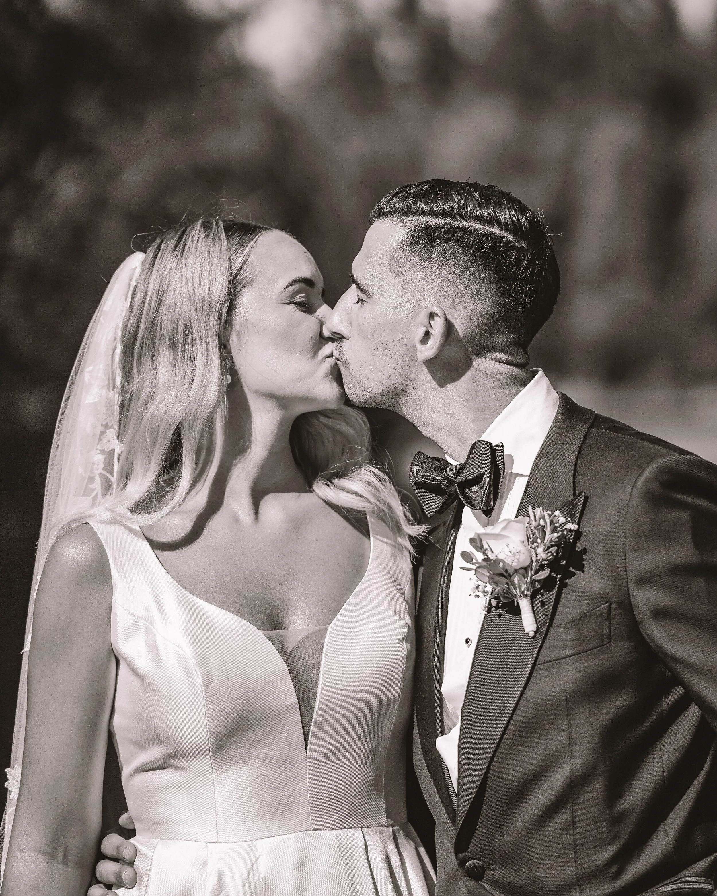 En svartvit bild av ett brudpar som kysser varandra.
